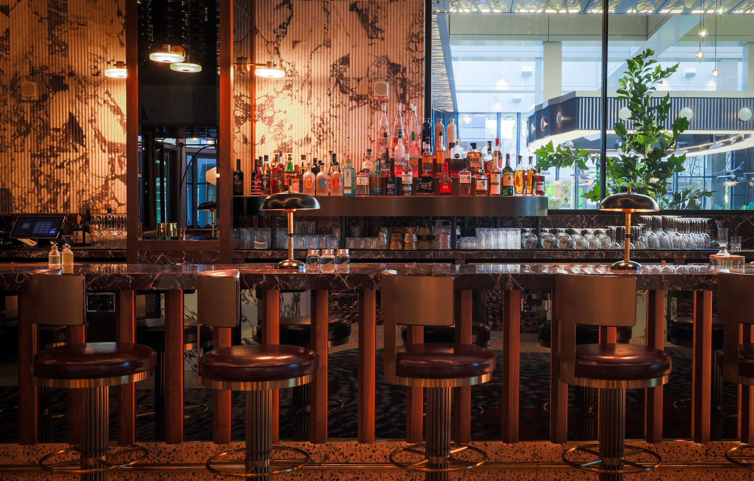 Figure 4: Gravitas (Beverly Hills) bar interior, defined by warm material tones, refined lighting, and a sculptural marble bar that anchors the space, balancing intimacy and openness within a contemporary hospitality setting