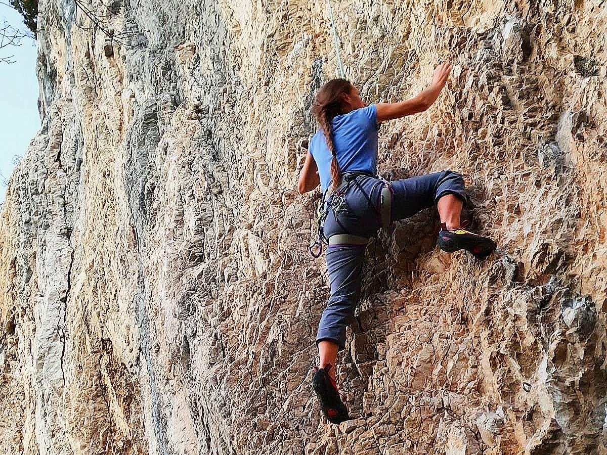 A woman rock climbing at a crag in Arco
