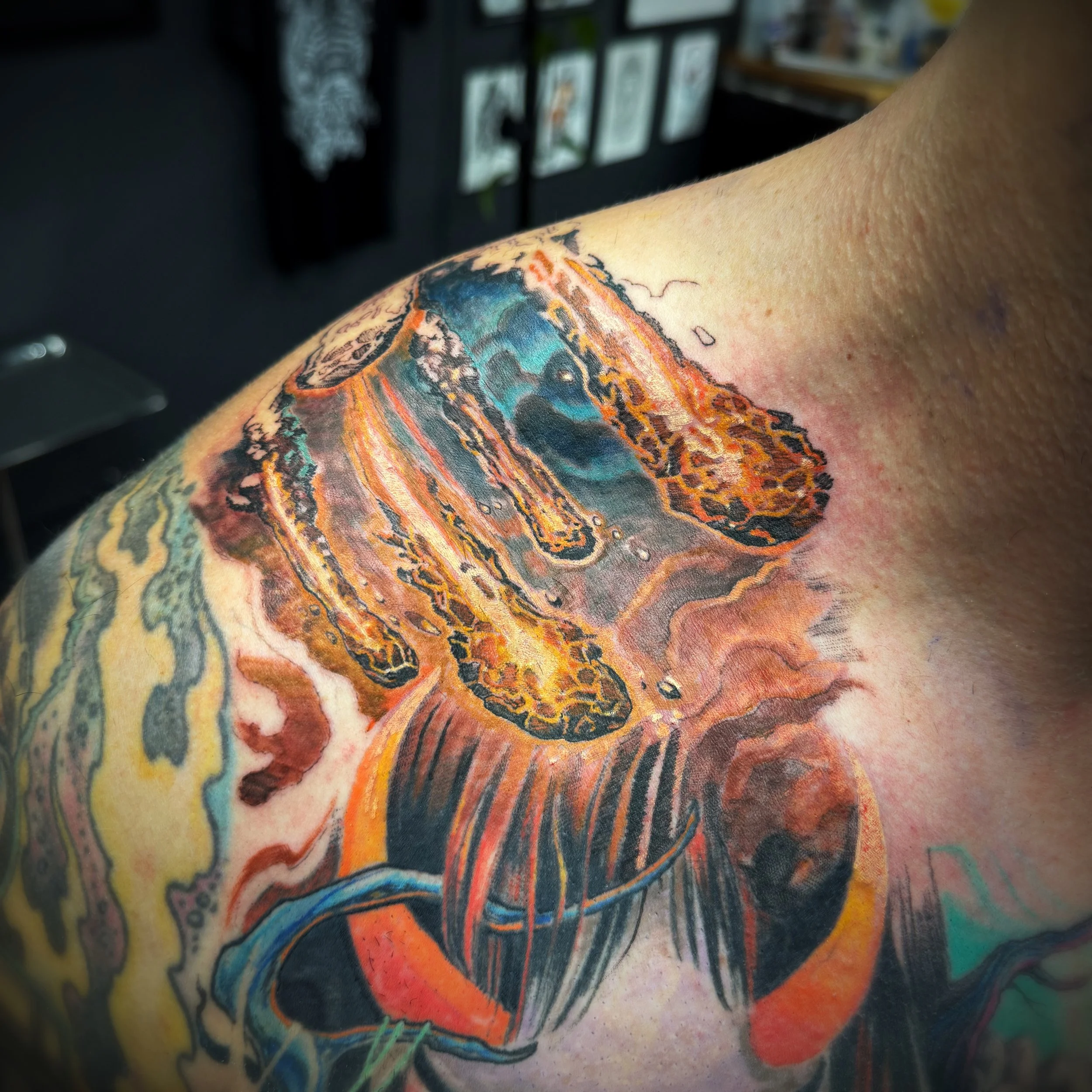 Close-up of a colorful tattoo on a person's arm, featuring abstract patterns and vibrant hues of orange, blue, and black.