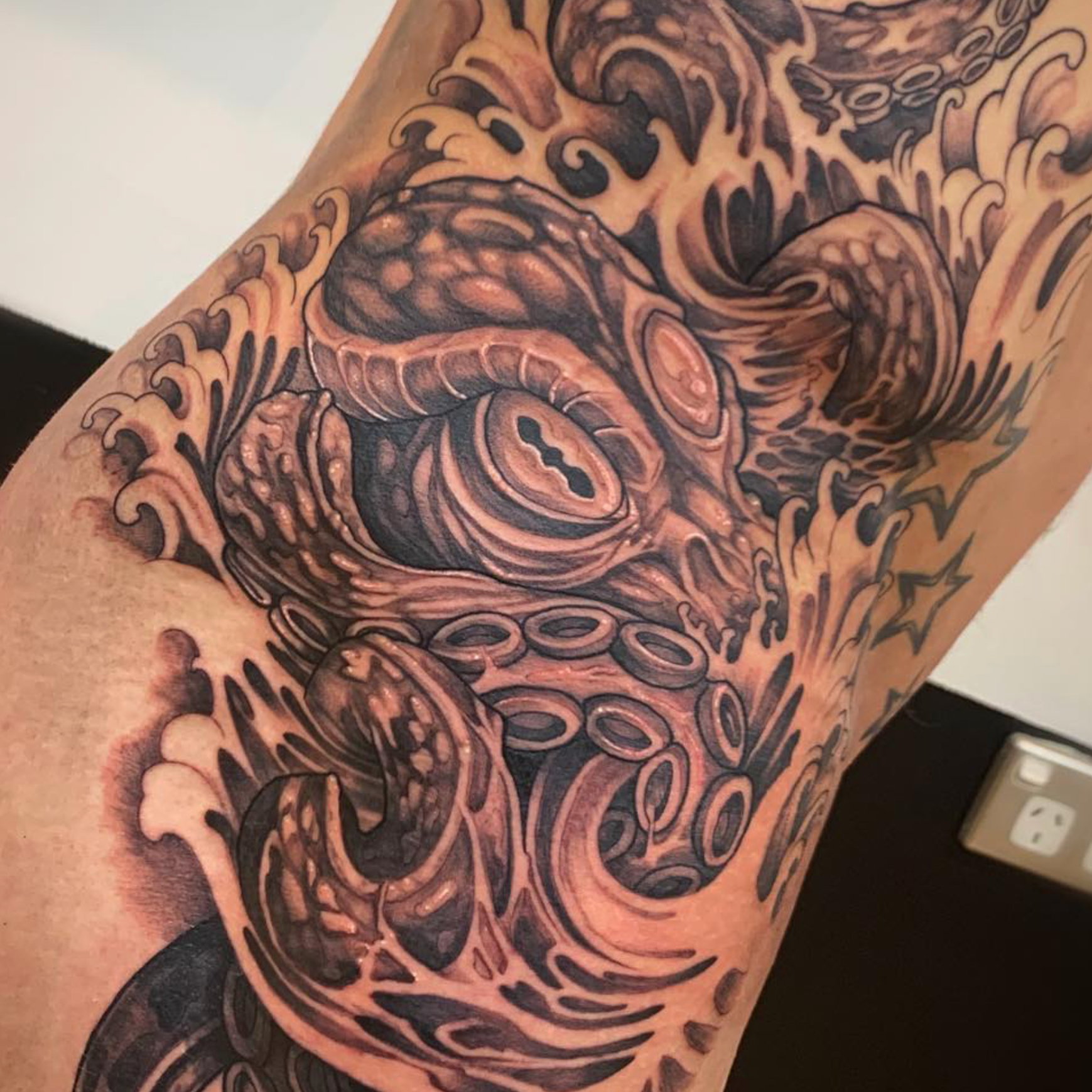 Tattoo of a giant octopus with swirling tentacles covering a person's upper arm and shoulder.