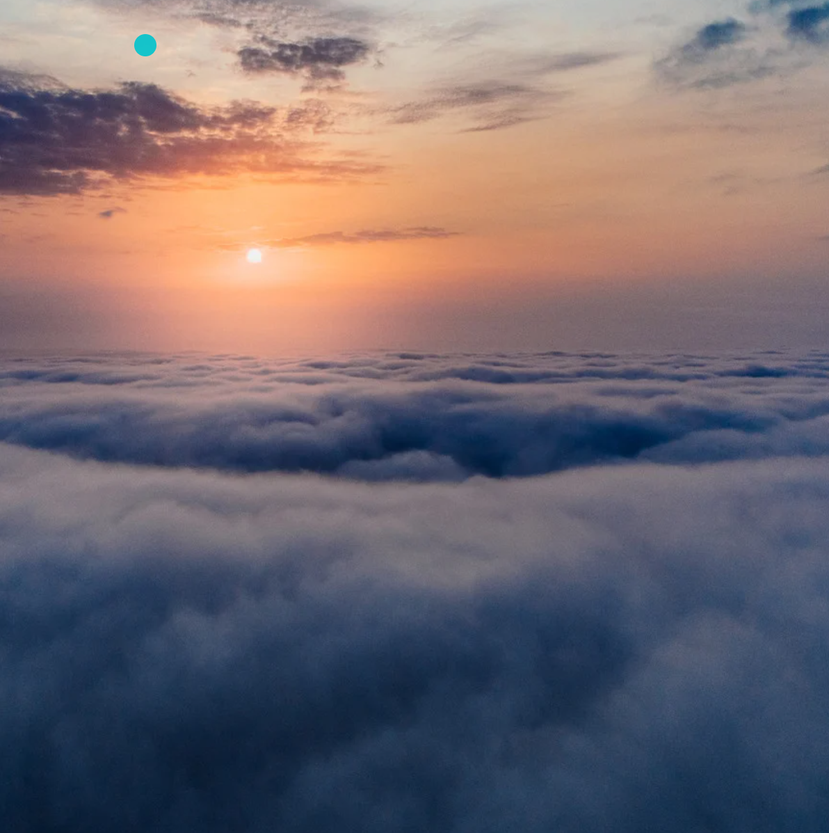 Sunrise over a sea of clouds with a pink and orange sky and some dark clouds.