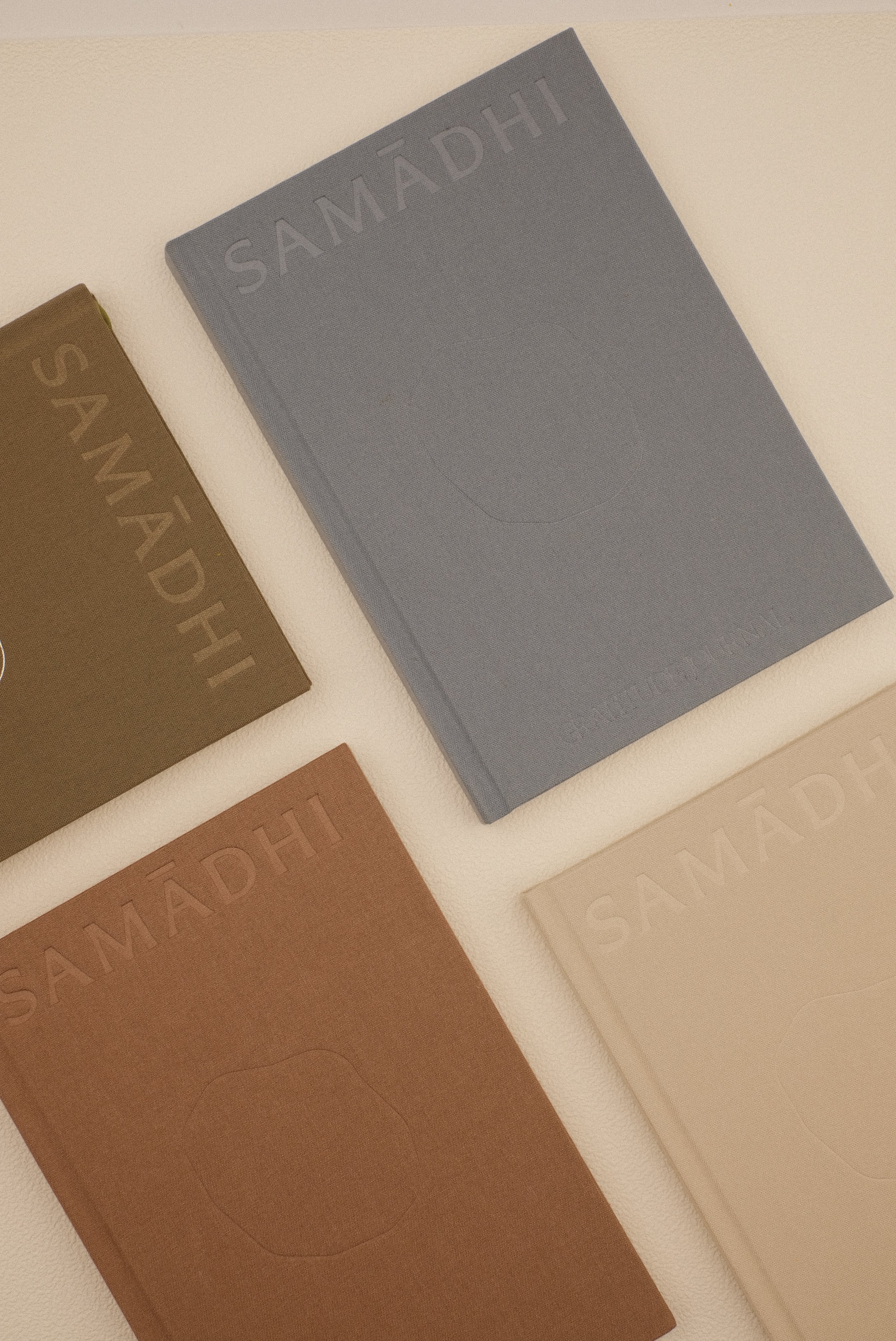 Four reflection journals, including open journals in dotted pattern sheets and a gratitude journal, with minimalist covers in different colors (brown, beige, blue) arranged with beige background.
