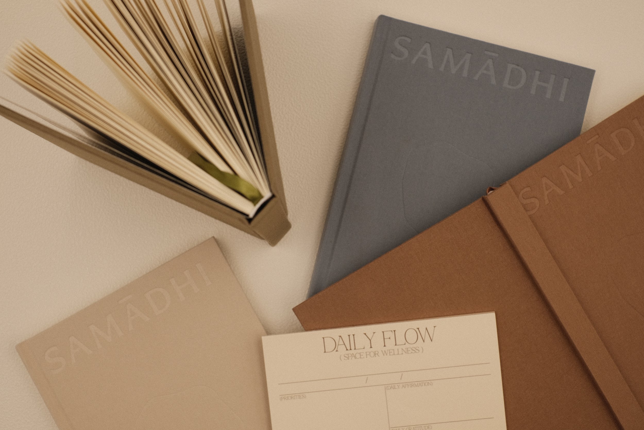 Reflection and gratitude journals and a daily wellness planner pad on a beige surface.