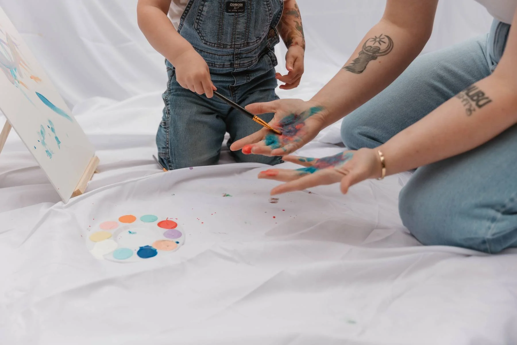 child painting on 1104 story studio owners hands with a paint brush
