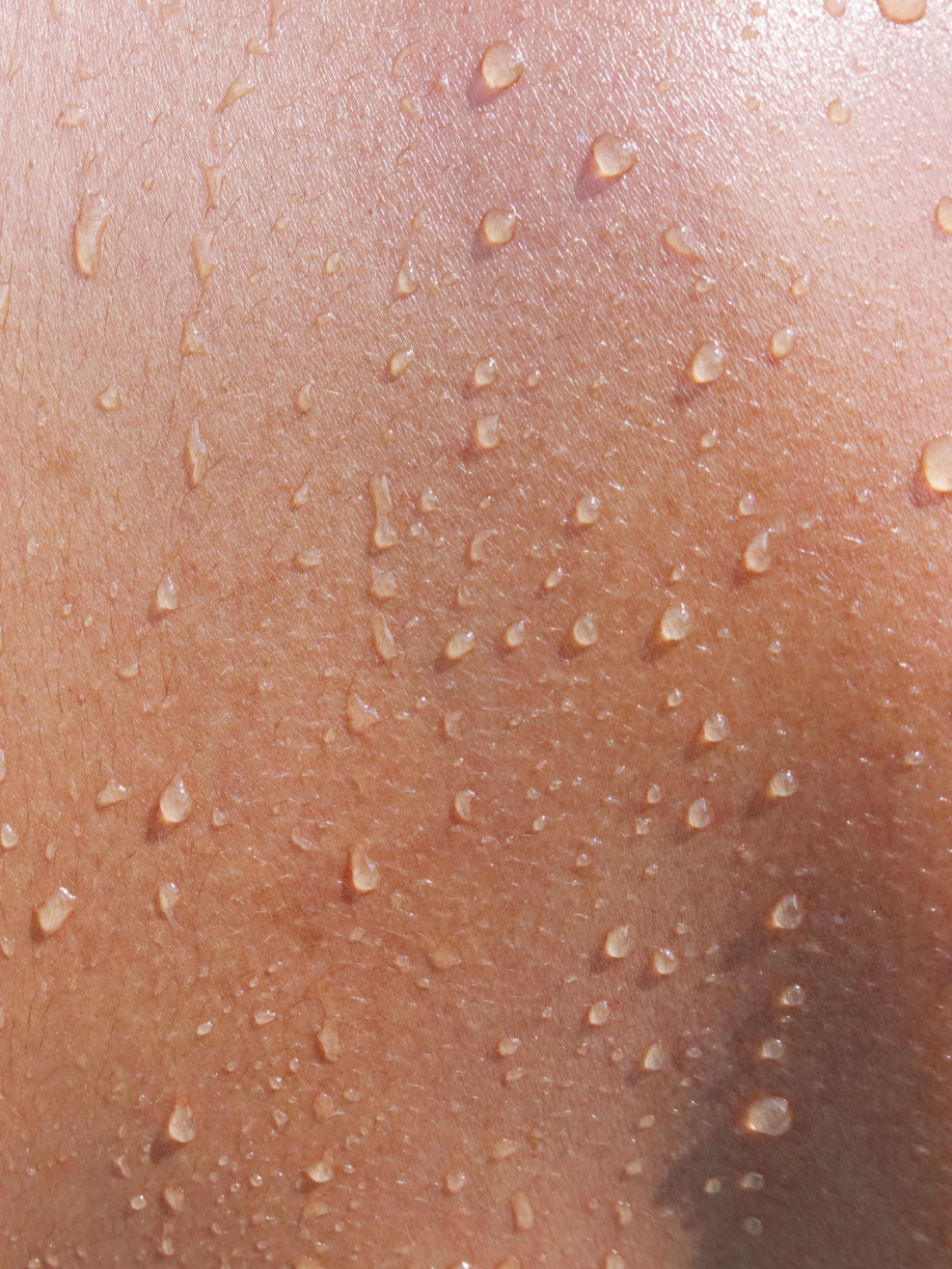 Close-up of human skin with water droplets on the surface.