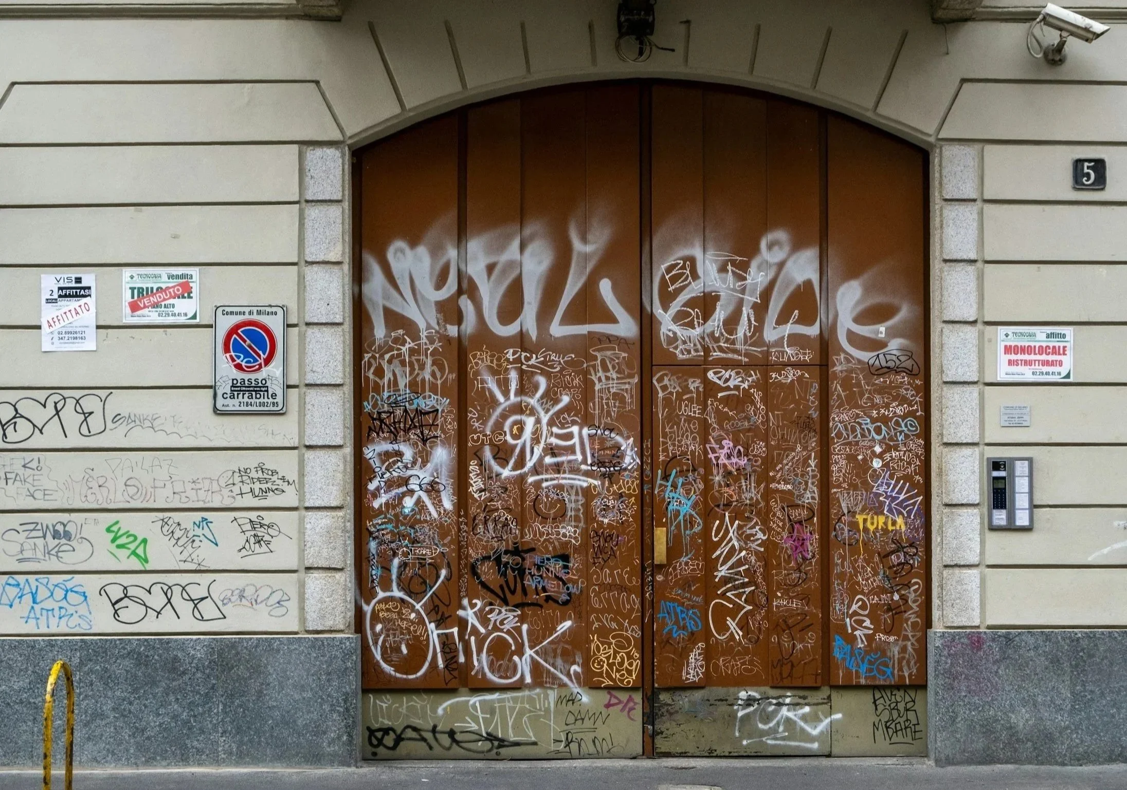 porte et mur recouvert de tags et graffitis à décaper