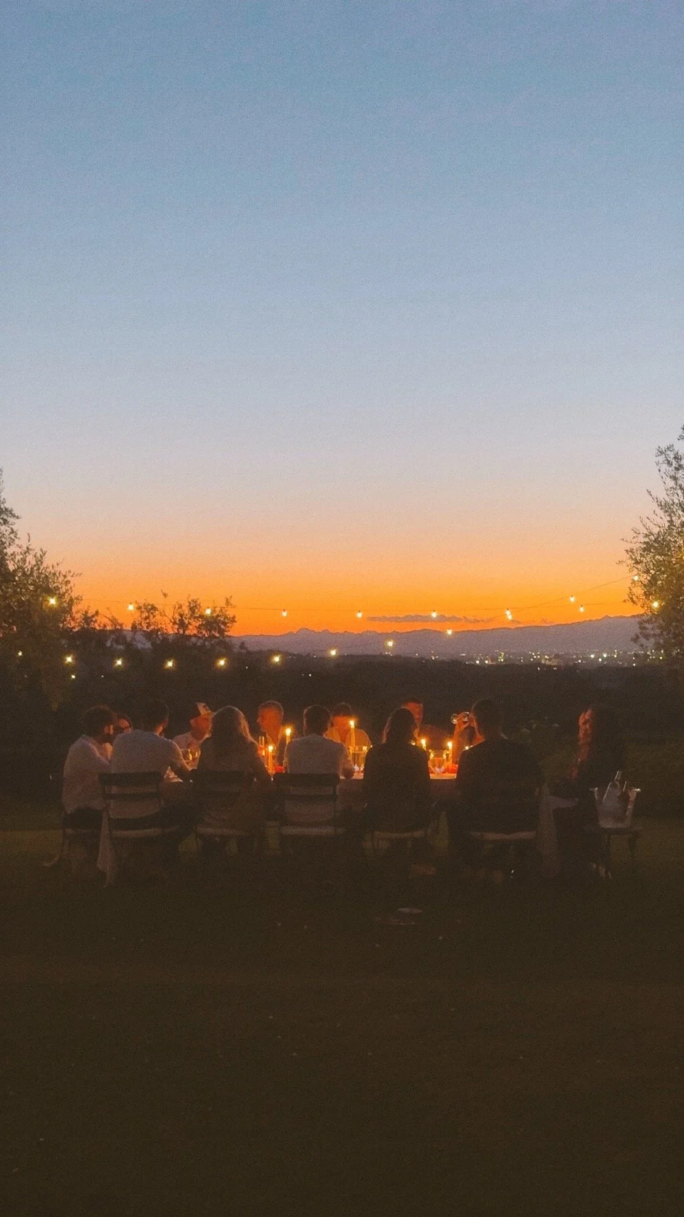Cena conviviale al tramonto in Toscana, esperienza gastronomica intima tra natura, luce calda e tavola curata.