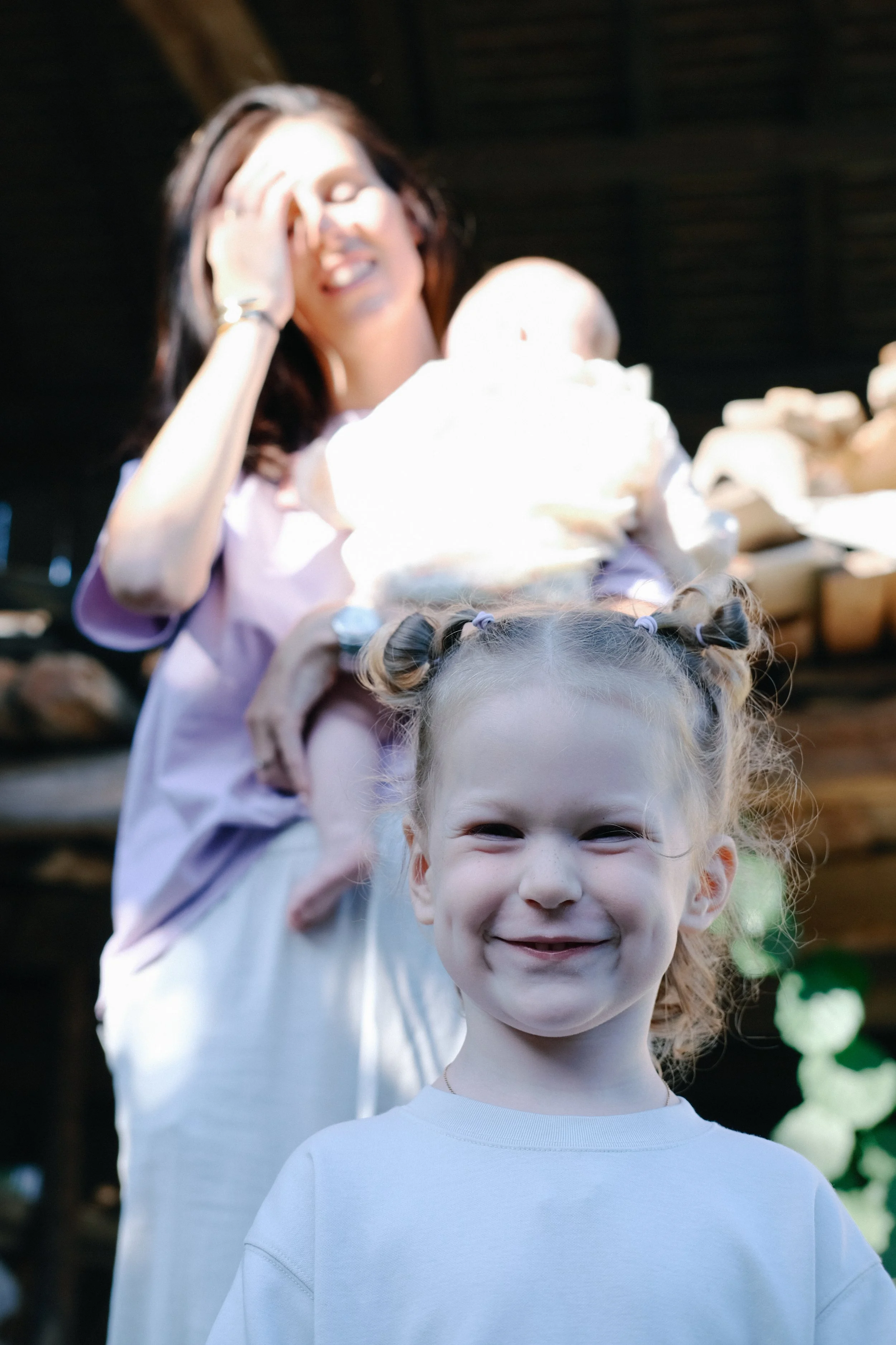 Deux jeunes filles souriantes, une avec des cheveux roux et l'autre avec des tresses, posant devant une structure en bois, probablement dans un espace extérieur.