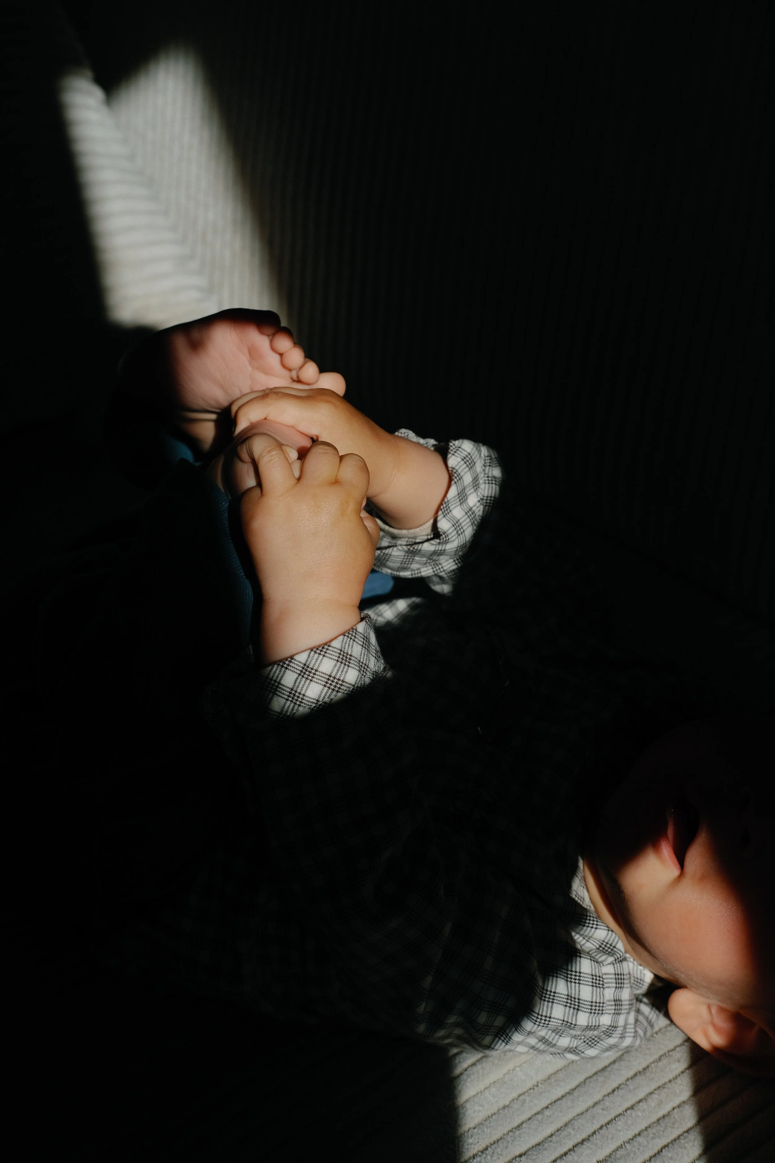 Deux enfants jouent, l'un en meuglant dans un téléphone et l'autre tenant la main de l'enfant en face. L'image est sombre avec une lumière qui éclaire partiellement leur main et leur visage, tous deux portant des vêtements à carreaux.