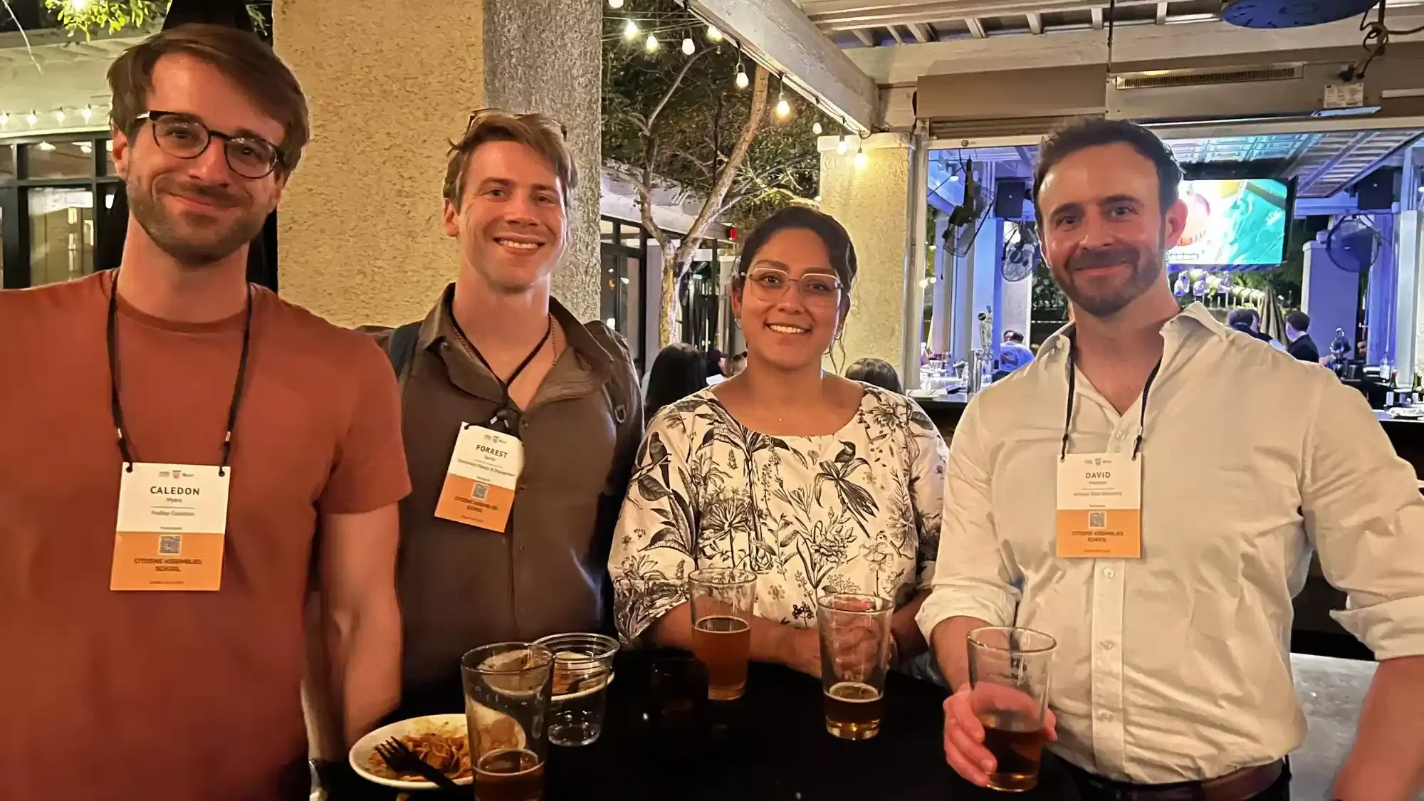 Image showing Caledon Myers on the left and three other people next to him standing at a high table and drinking at the Phoenix School 2024. The quote on the right of the image belongs to him.