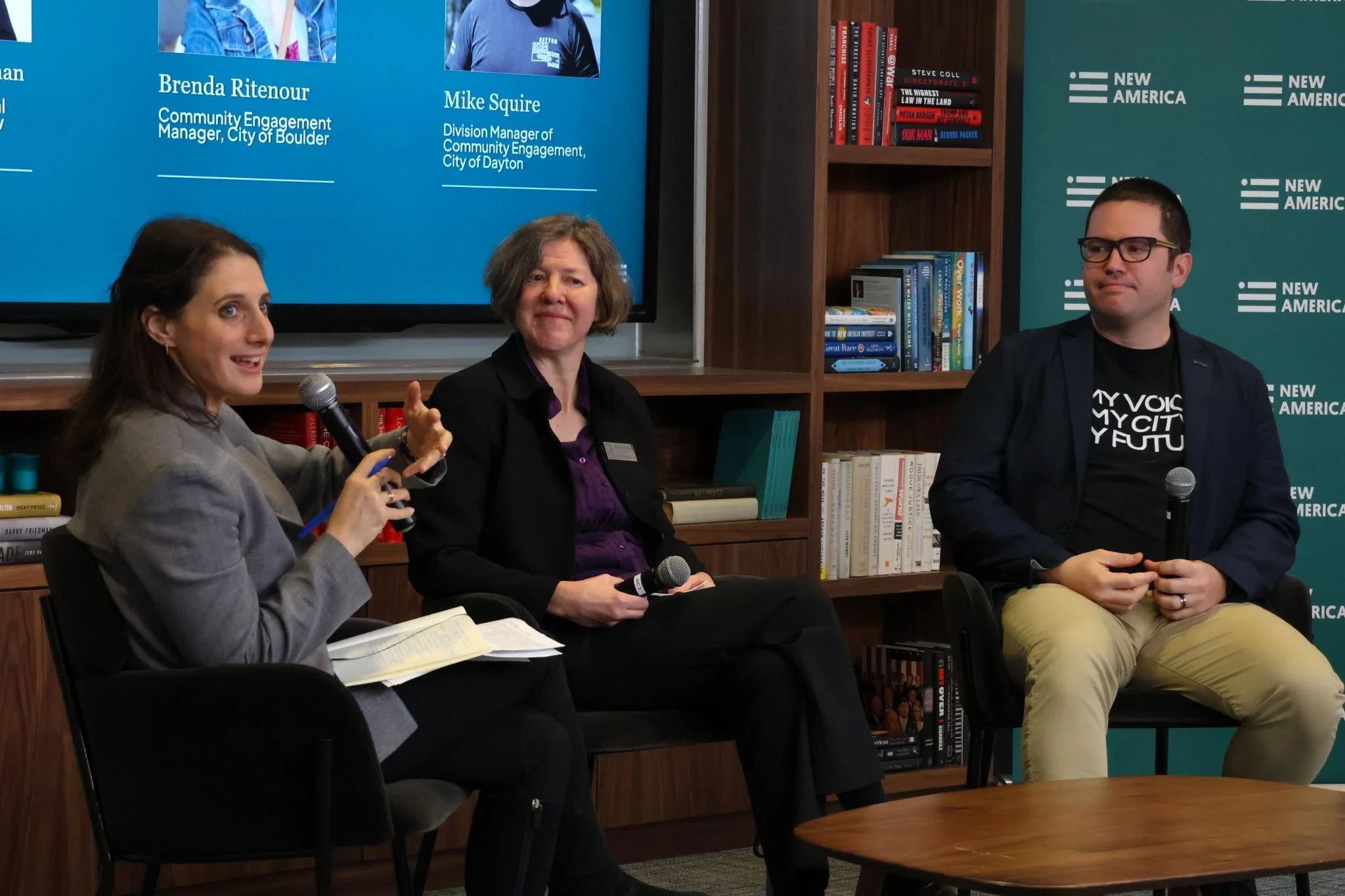 Three speakers sitting at a table at a panel discussion. Photo was taken at the Wisdom of the Crowds event.