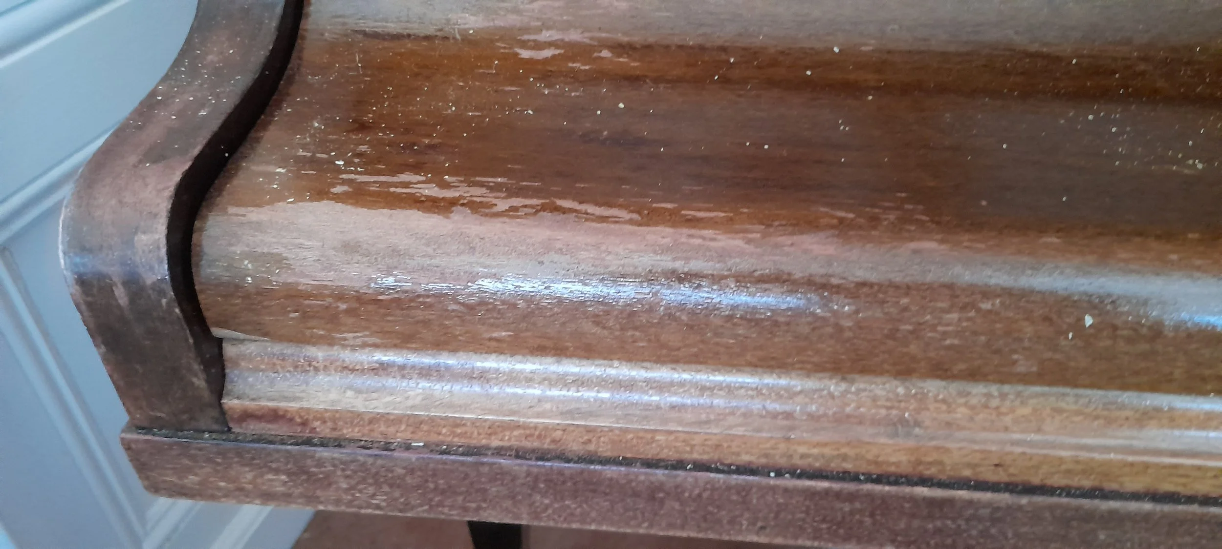 Picture of front of a grand piano showing water damage to lid