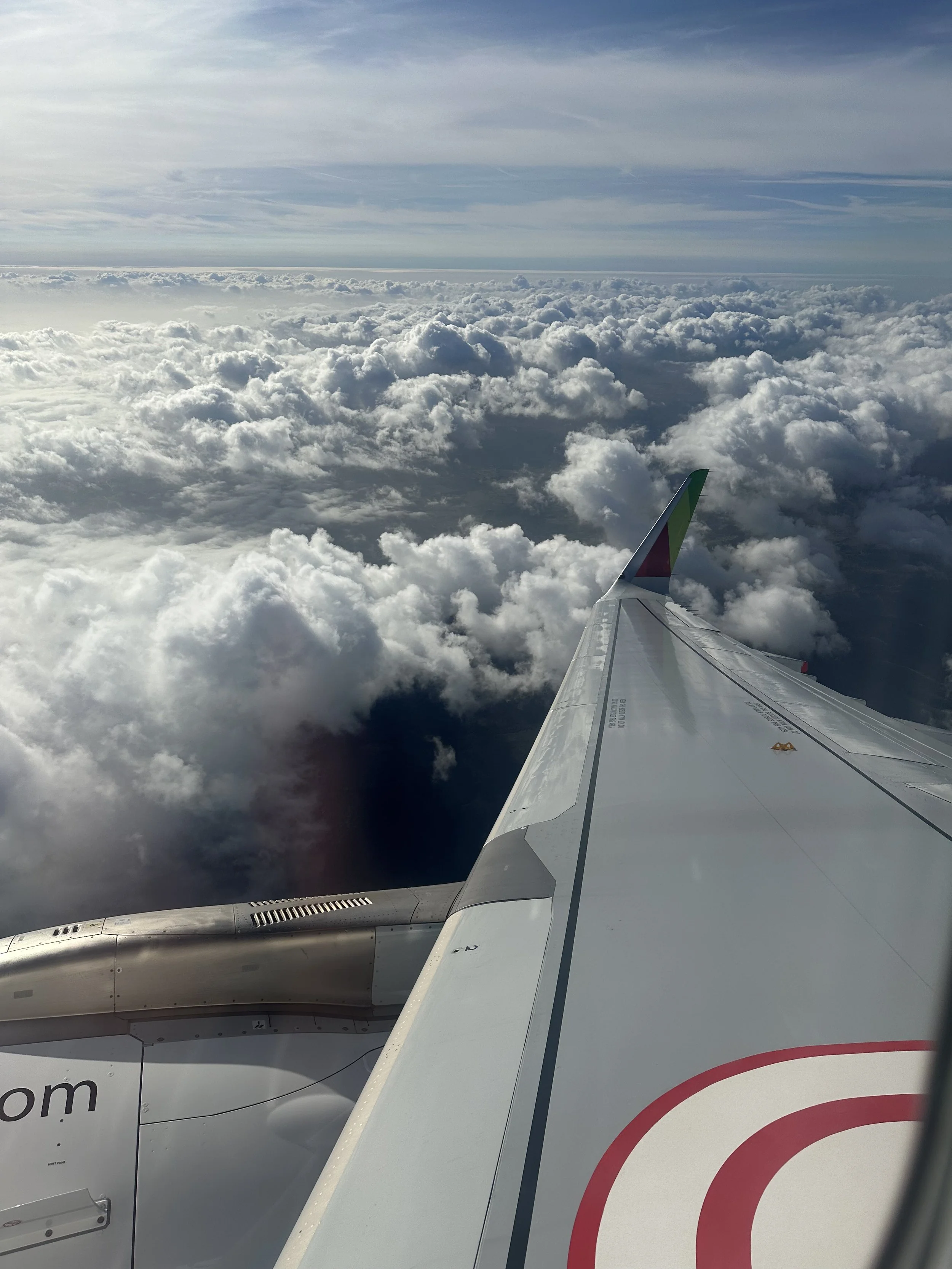 View looking through the window of the plane looking at the wing of the plane as it goes through the clouds.