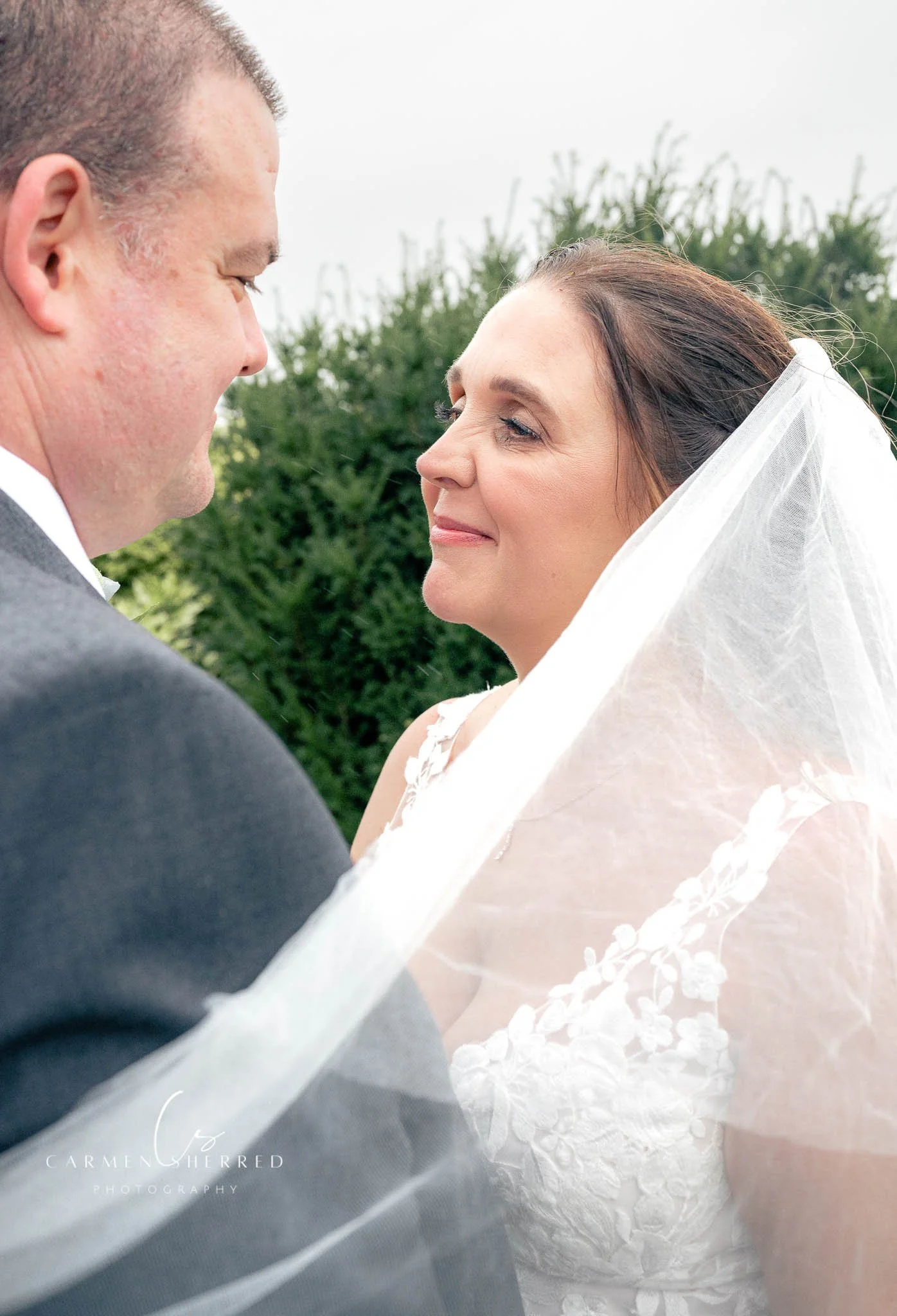 A bride and groom gazing at each other during their wedding ceremony outdoors.