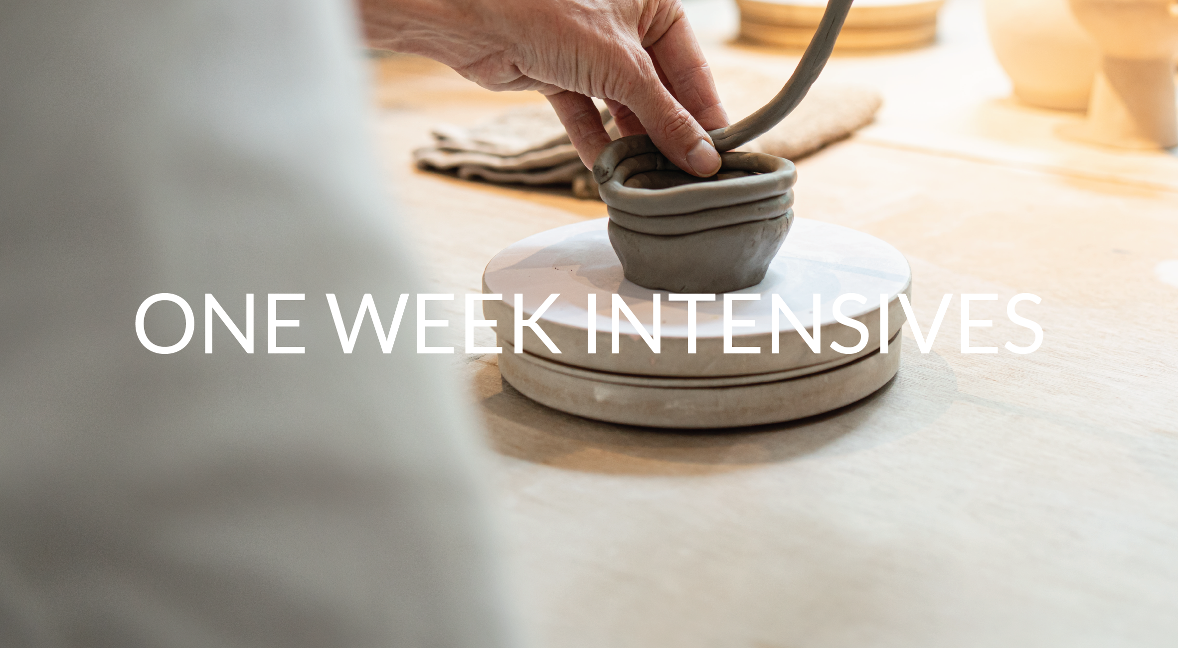 Person shaping a ceramic bowl on a pottery wheel in a studio setting.