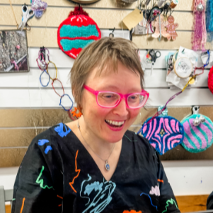 Lady with pink glasses smiling at a lapt top having fun