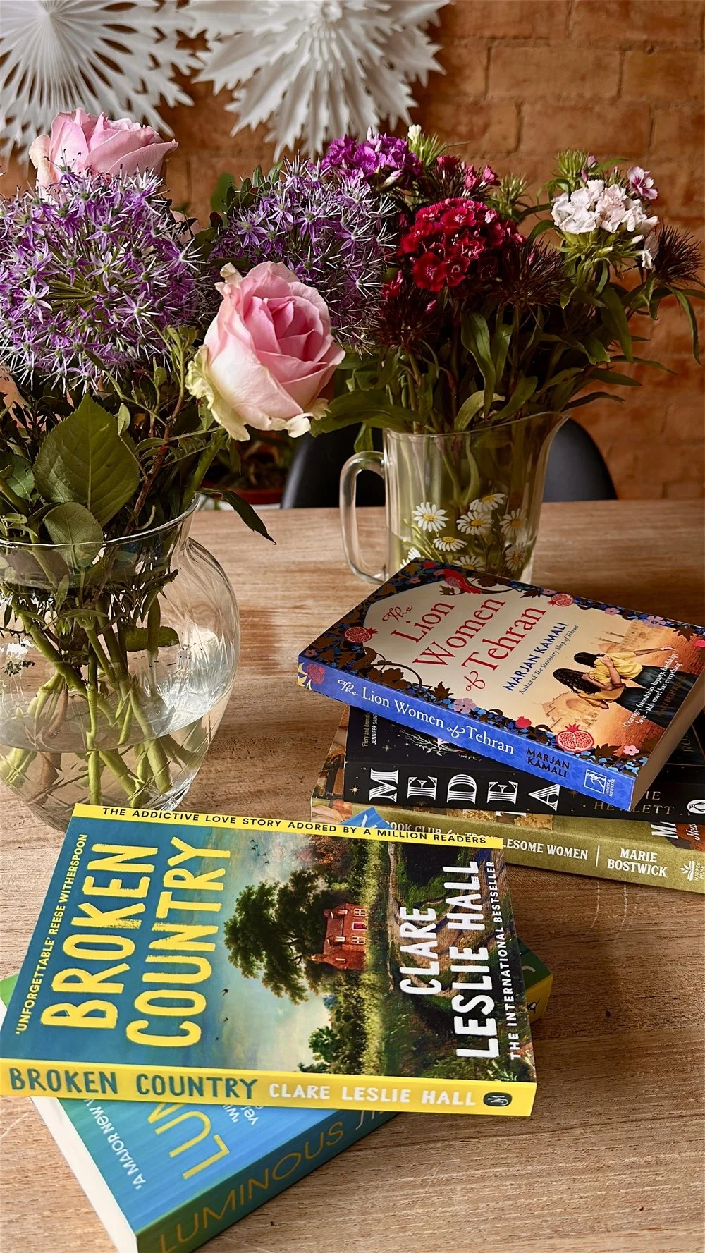 pile of books with vases of flowers