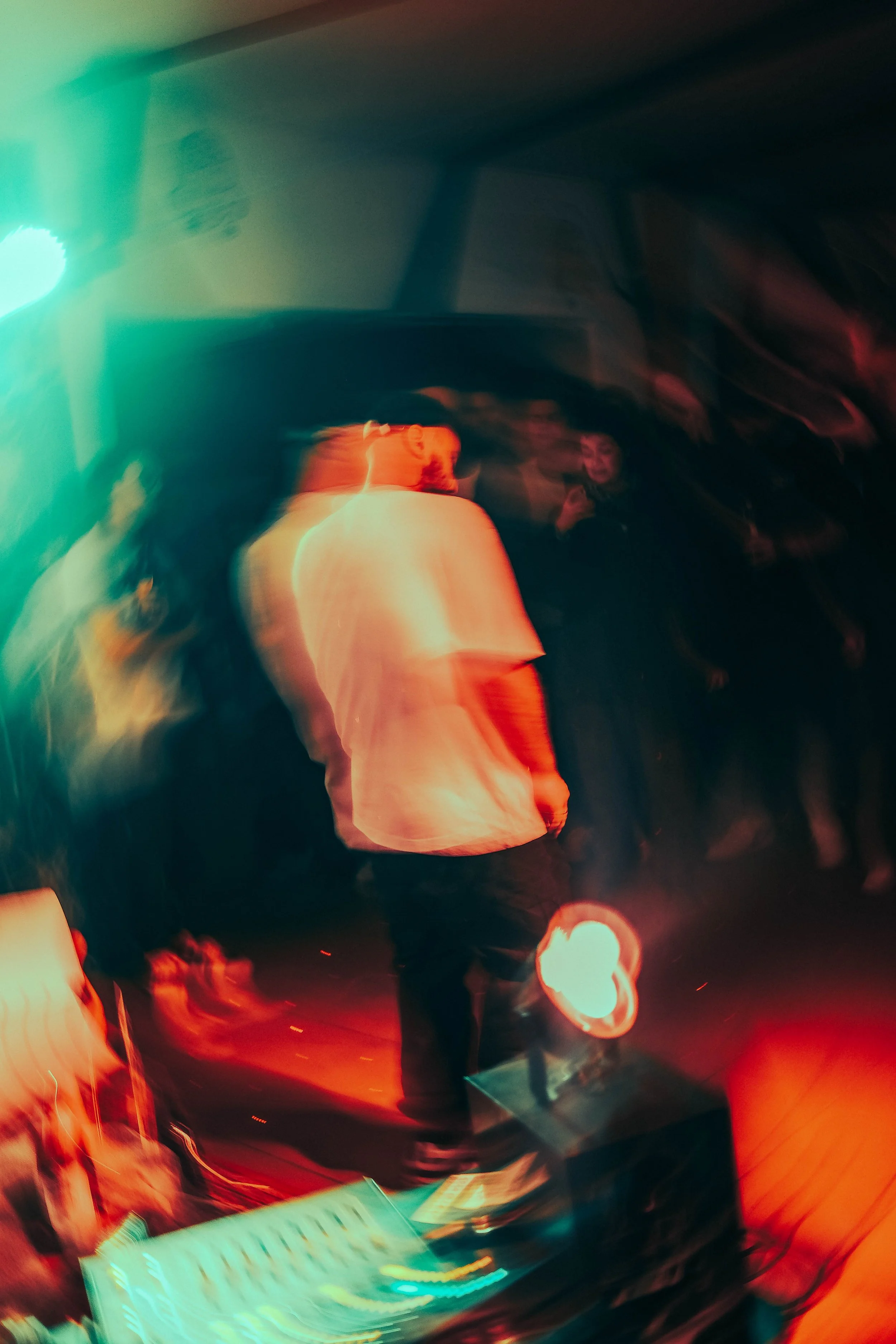 Abstraktes Foto einer Person, die an einem DJ-Set steht, in bunten Lichtern auf einer Party oder einem Club, mit bewegungsunschärfe für dynamischen Effekt.