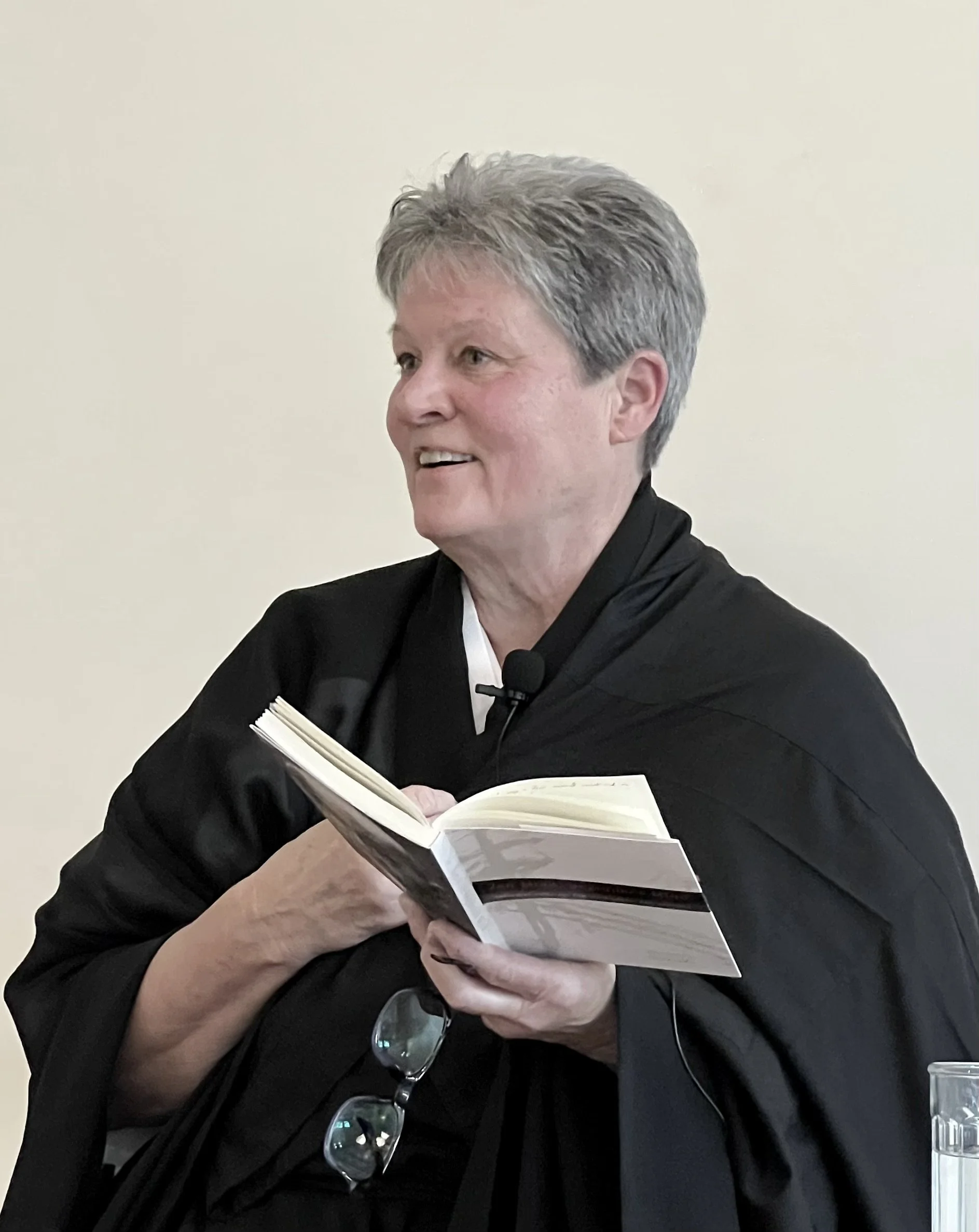 A woman dressed in judicial robes holding a book during a court proceeding.