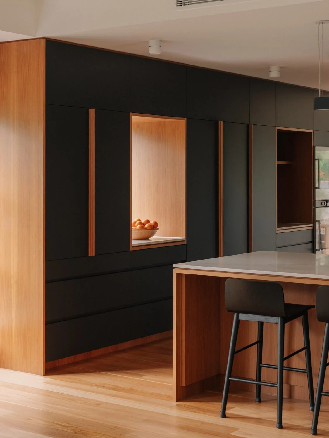 Modern kitchen with black and wood cabinets and a white countertop island