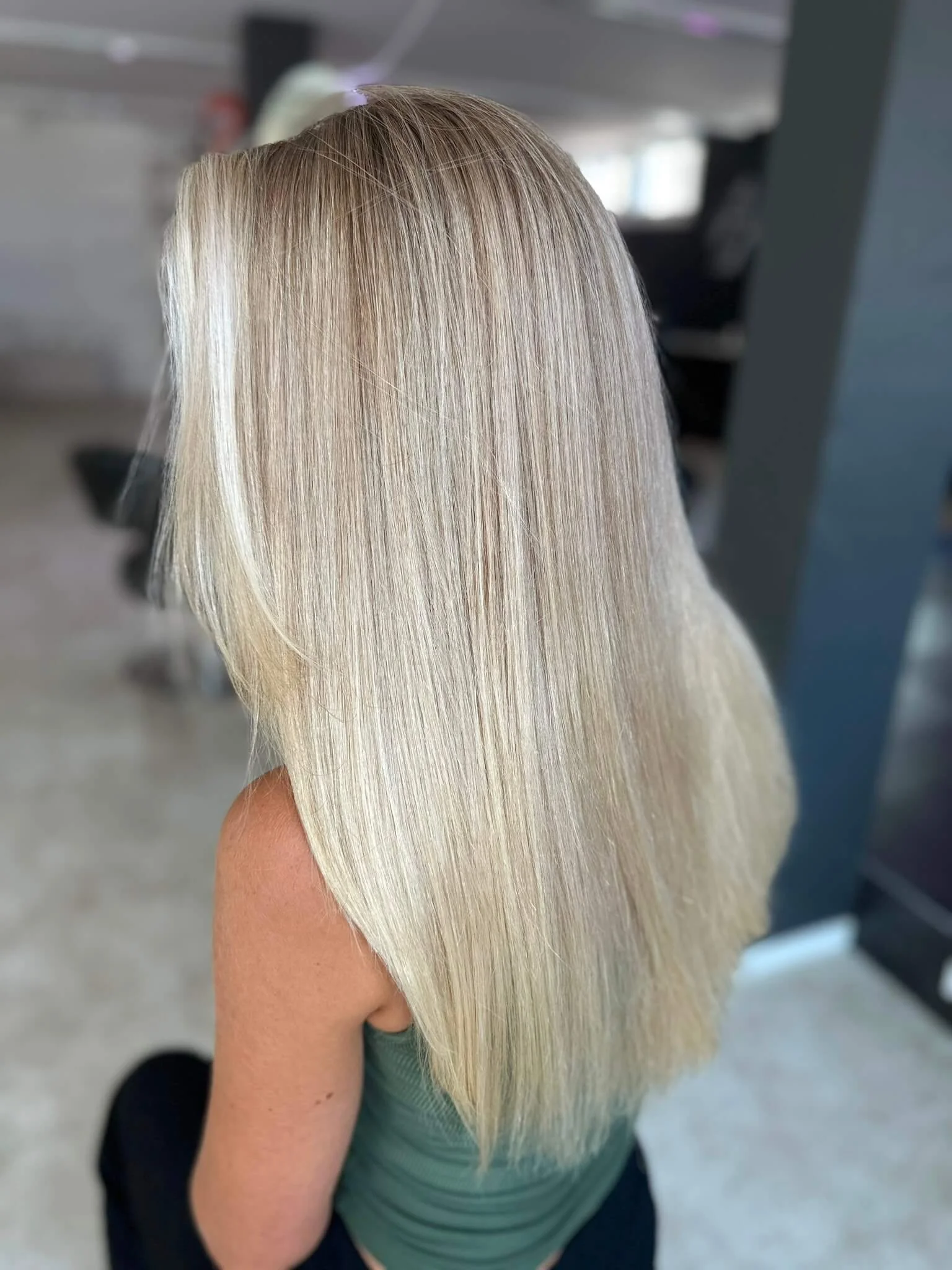 Eine Frau mit langen, glatten, platinblonden Haaren, die nach hinten über den Rücken fallen.