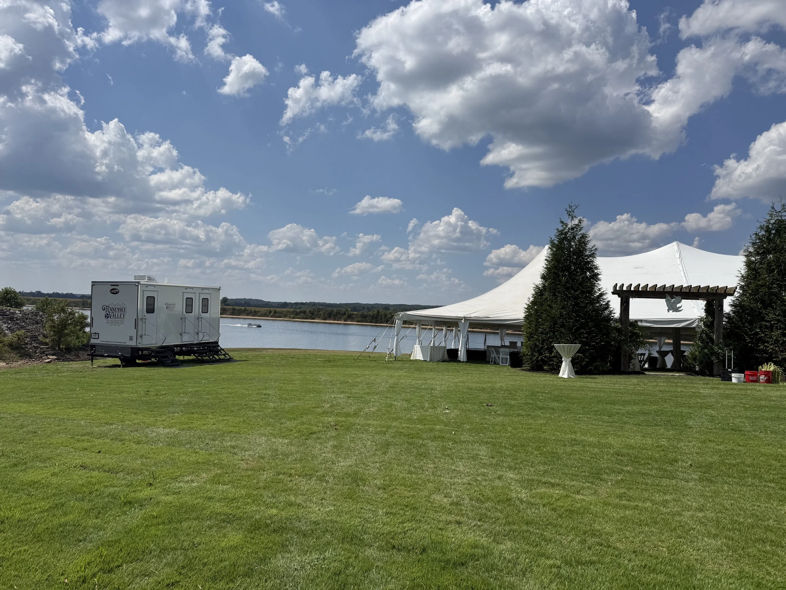 mobile restroom outside on the grass at a wedding