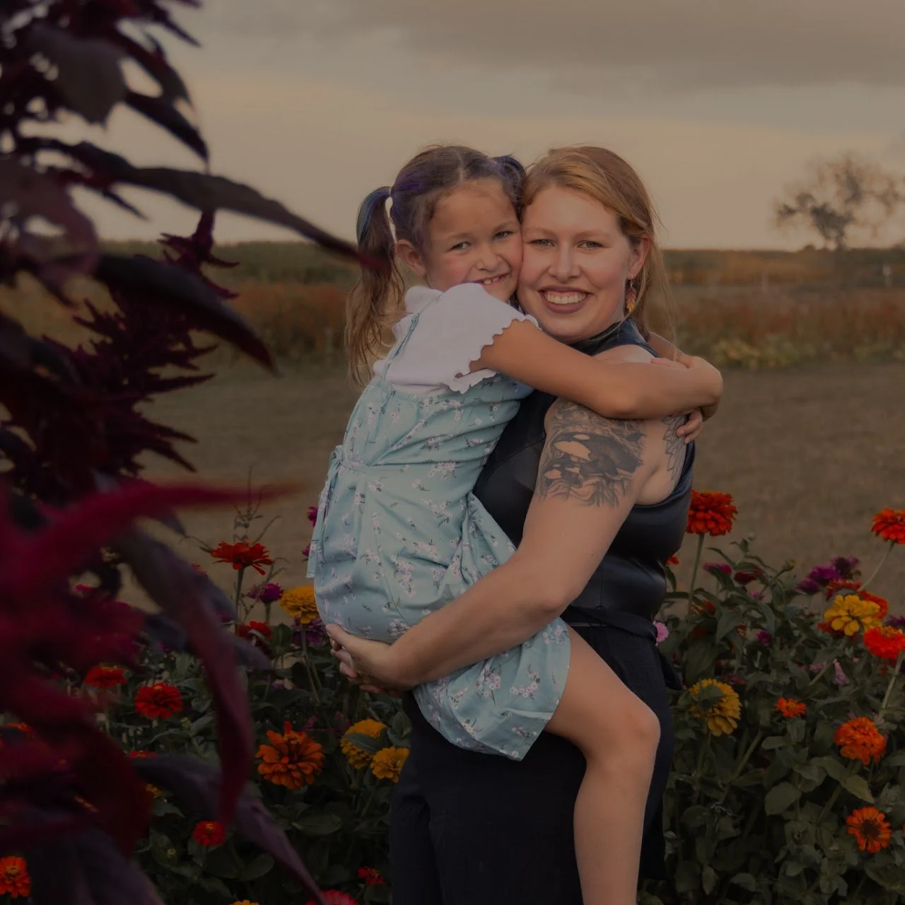 A mothers holds her young daughter, smiling.