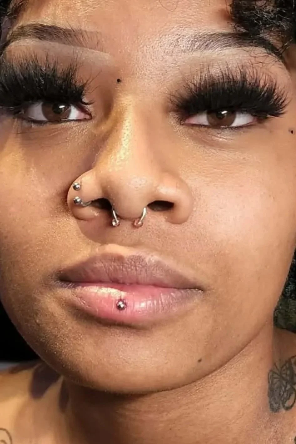 A woman with a septum, nostril, and vertical lip piercing.