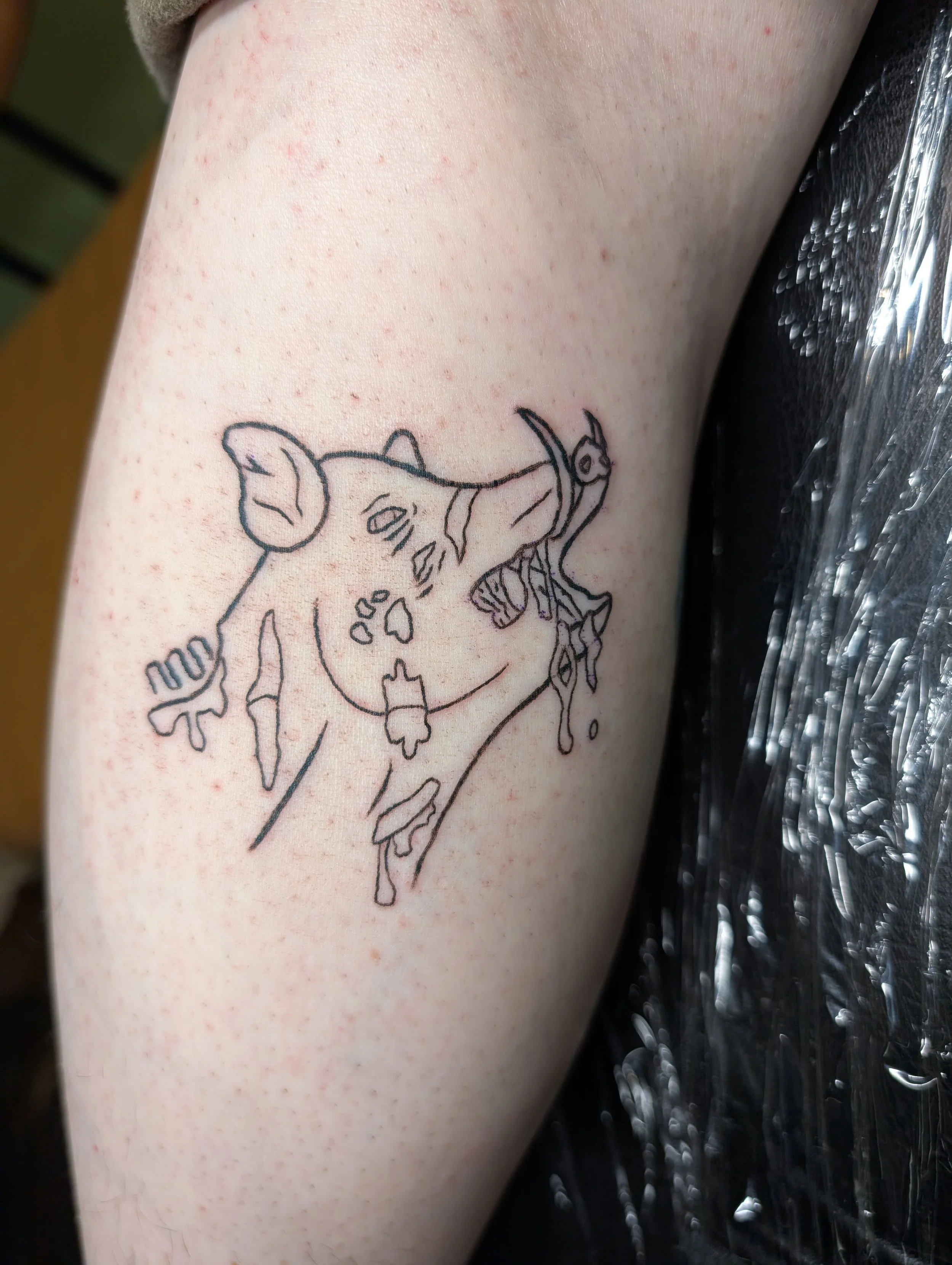 An outline tattoo of a boar with flesh falling of its face and drool coming from its mouth.