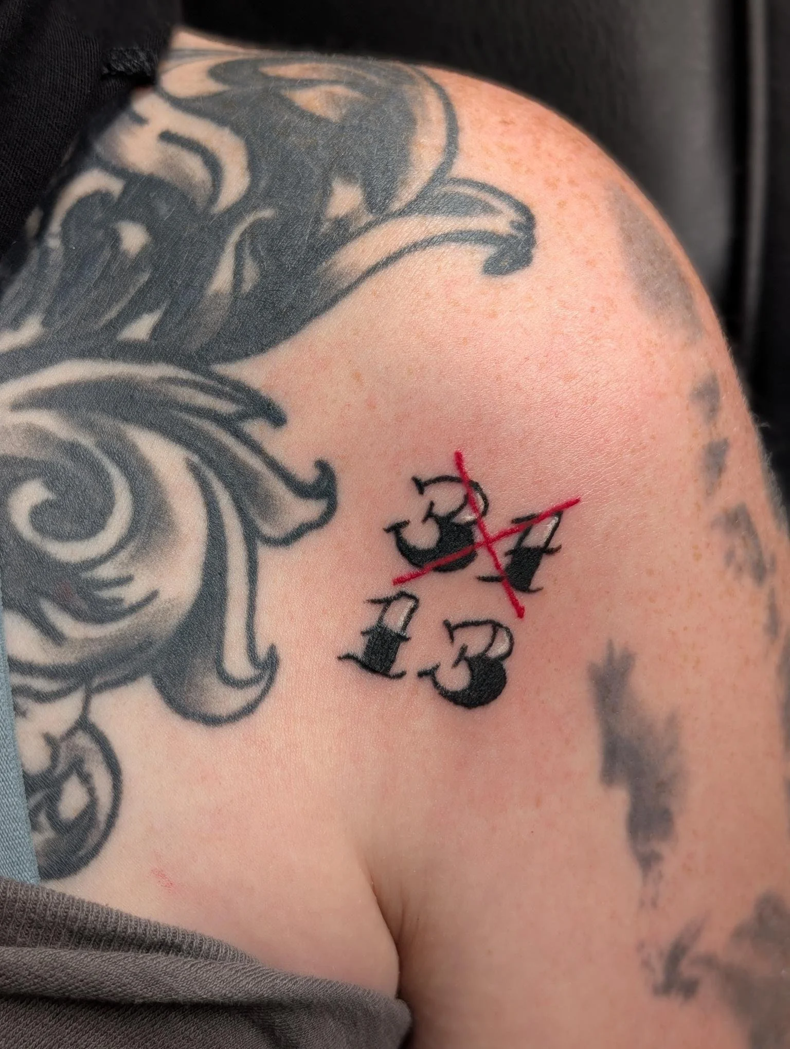A tattoo of the numbers 31 and 13 with a red 'X' over the 31. 