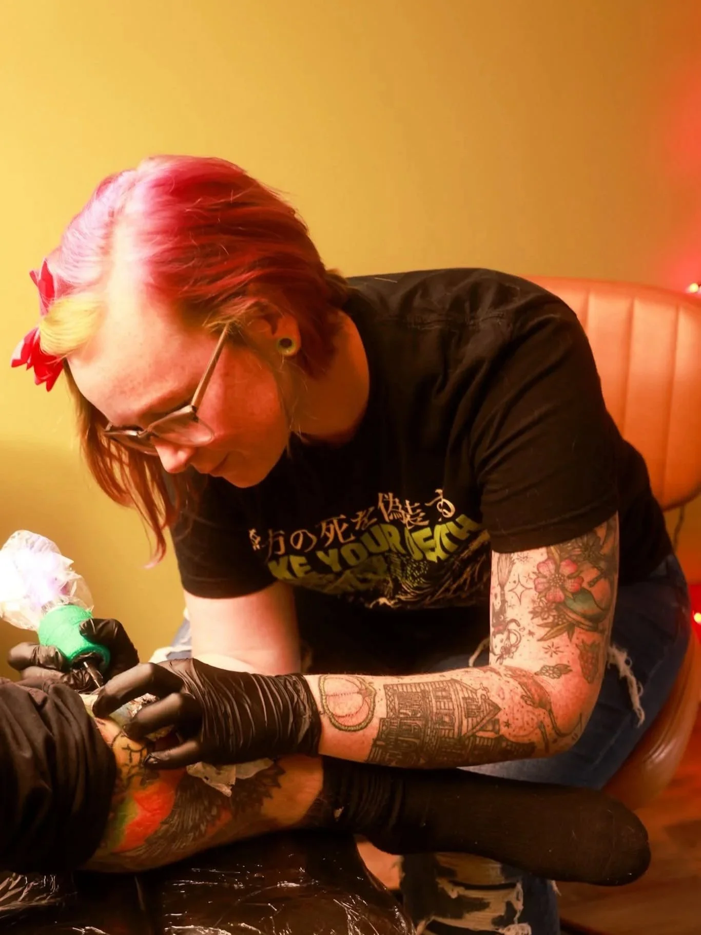 Mel focuses as she tattoos a client's leg.
