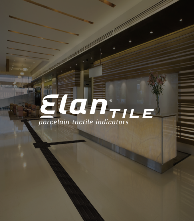 Modern hotel lobby with cream-colored tiled floor, wooden wall accents, and a reception desk with floral arrangement