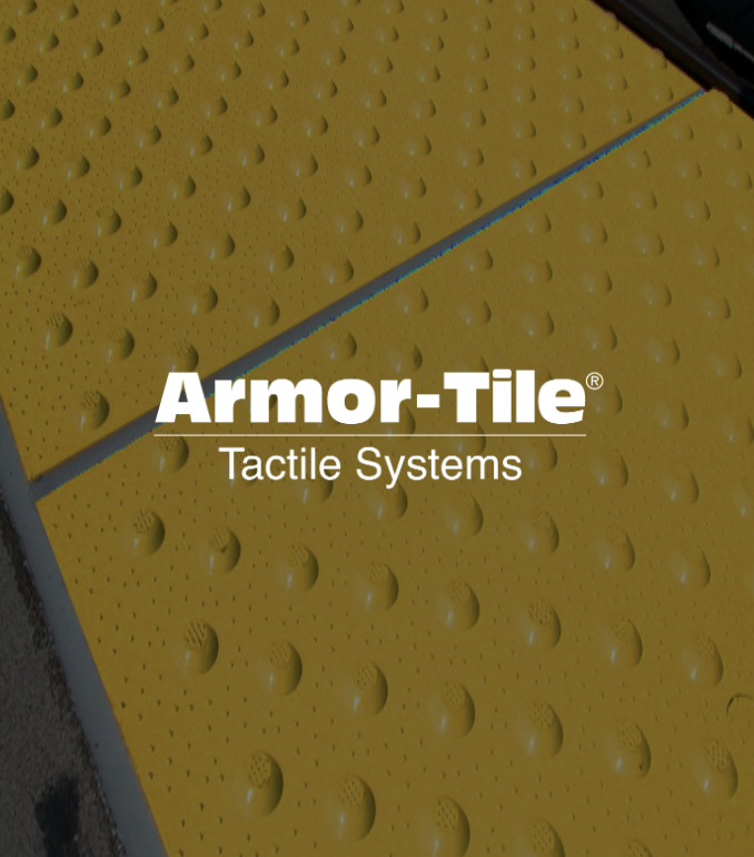 Close-up of yellow tactile paving tiles with raised domes, installed on a sidewalk or pedestrian crossing area.