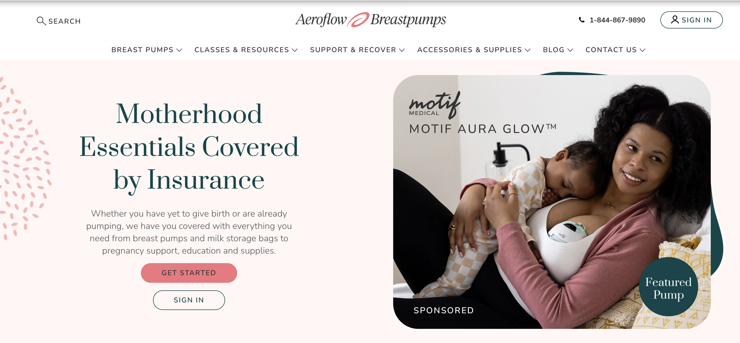 A woman lying on her side, breastfeeding her young child while lying on a bed, with a breast pump attached to her breast. The woman has curly black hair and a gentle smile. The setting appears to be a bedroom or a cozy home environment.