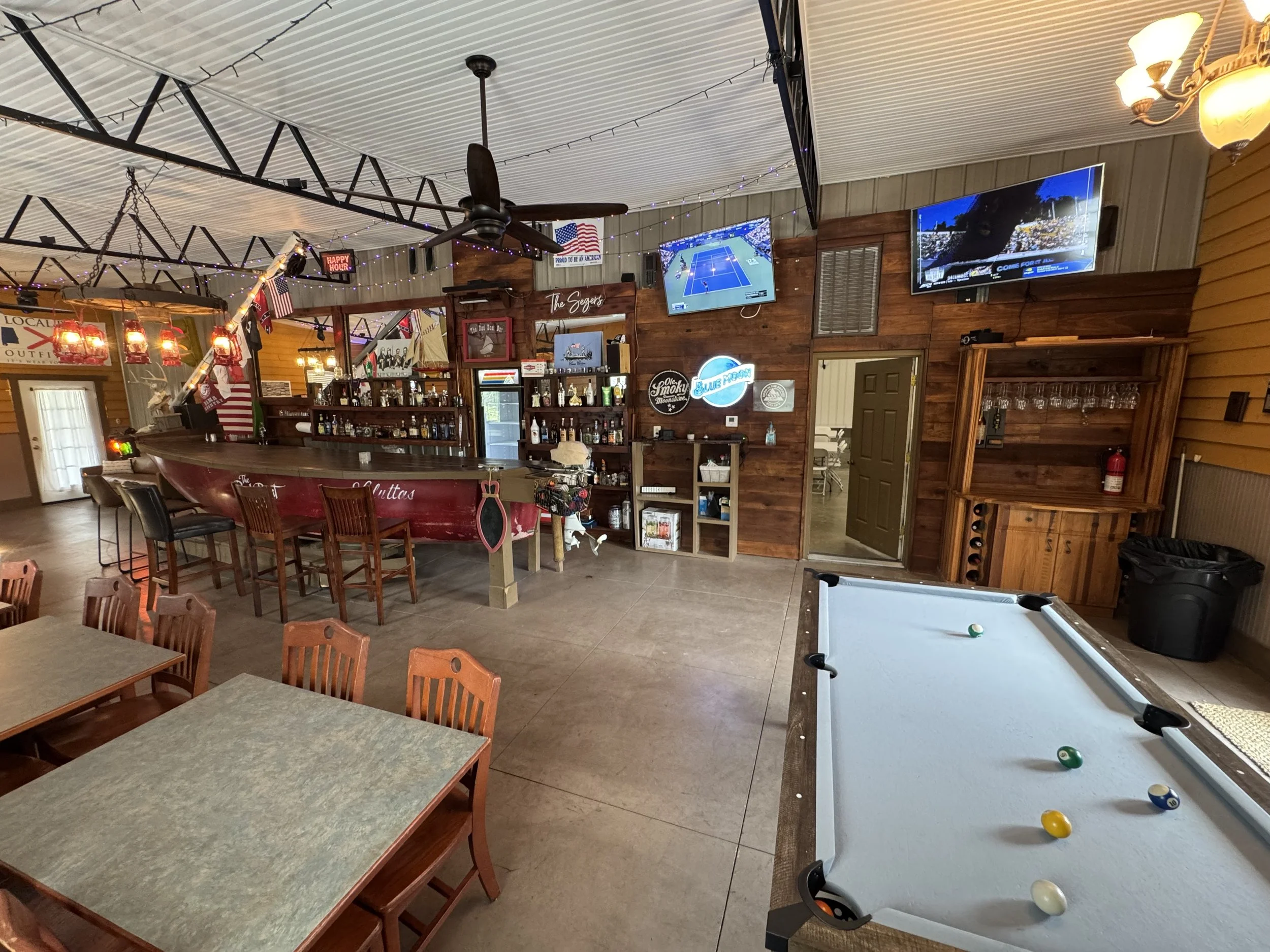Interior of a bar or restaurant with pool table, TV screens, wooden decor, and seating area.