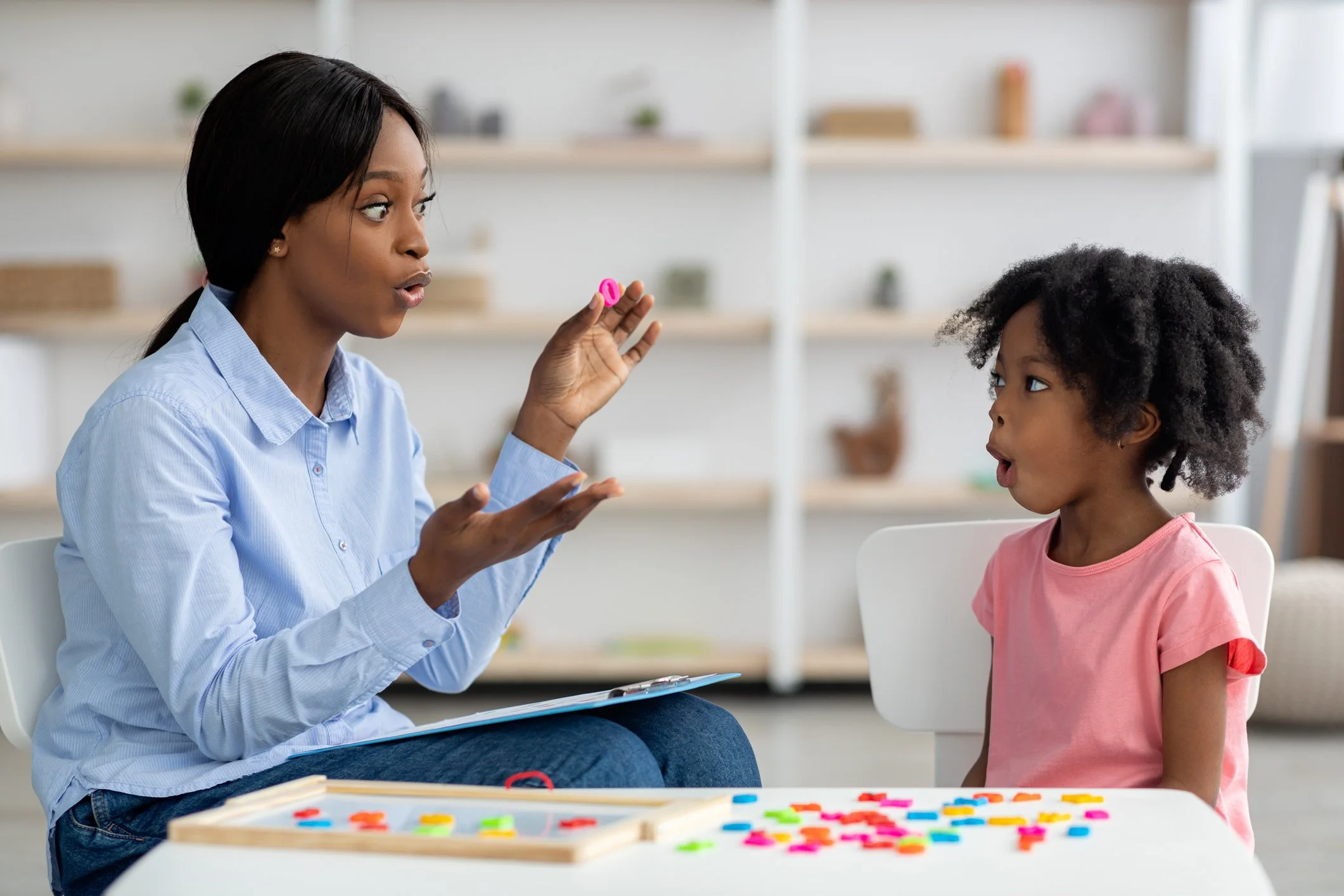 Speech-language pathologist conducting pediatric speech therapy session using flashcards with a young girl