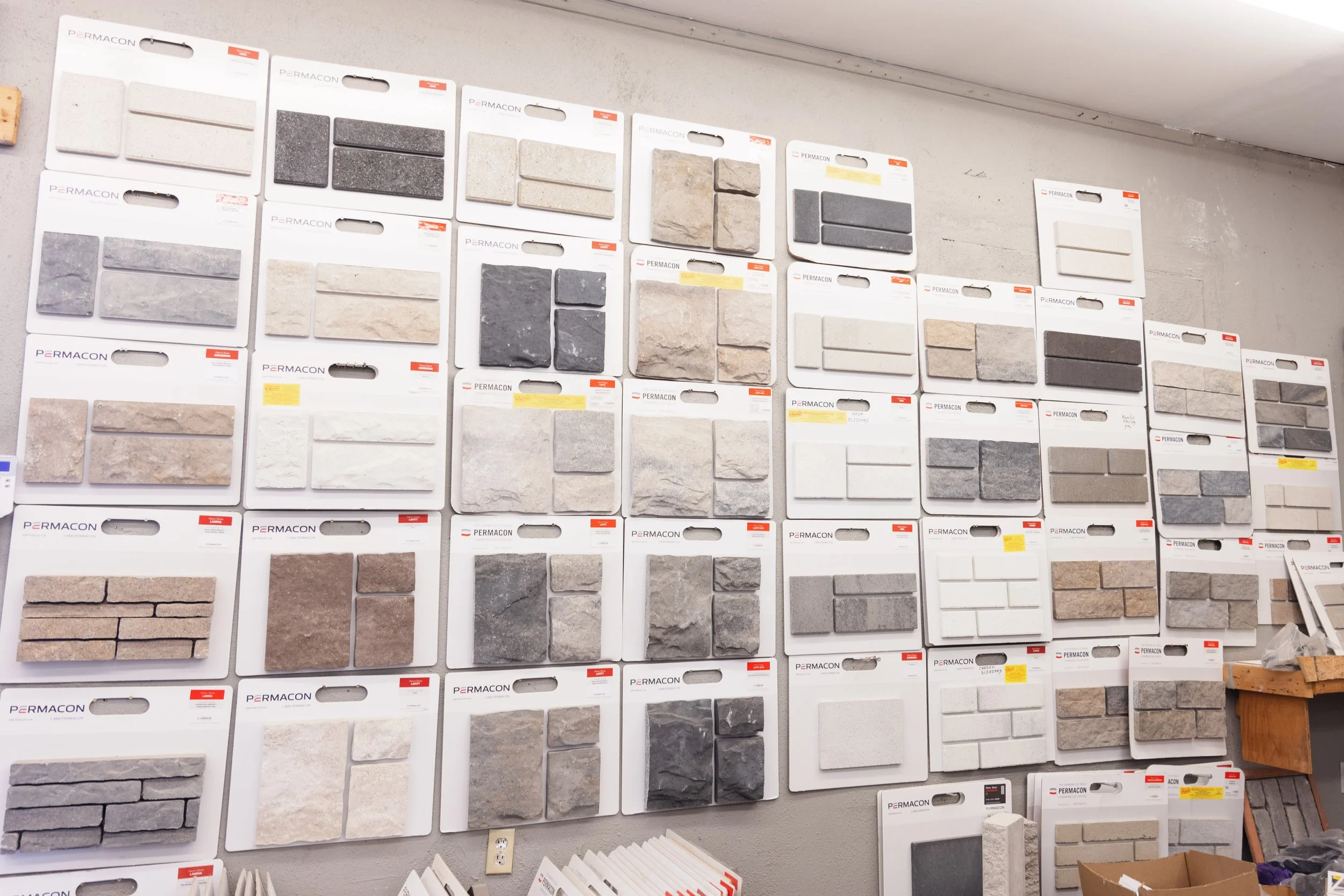 Display of various tile samples on a store wall, including different colors, textures, and styles.