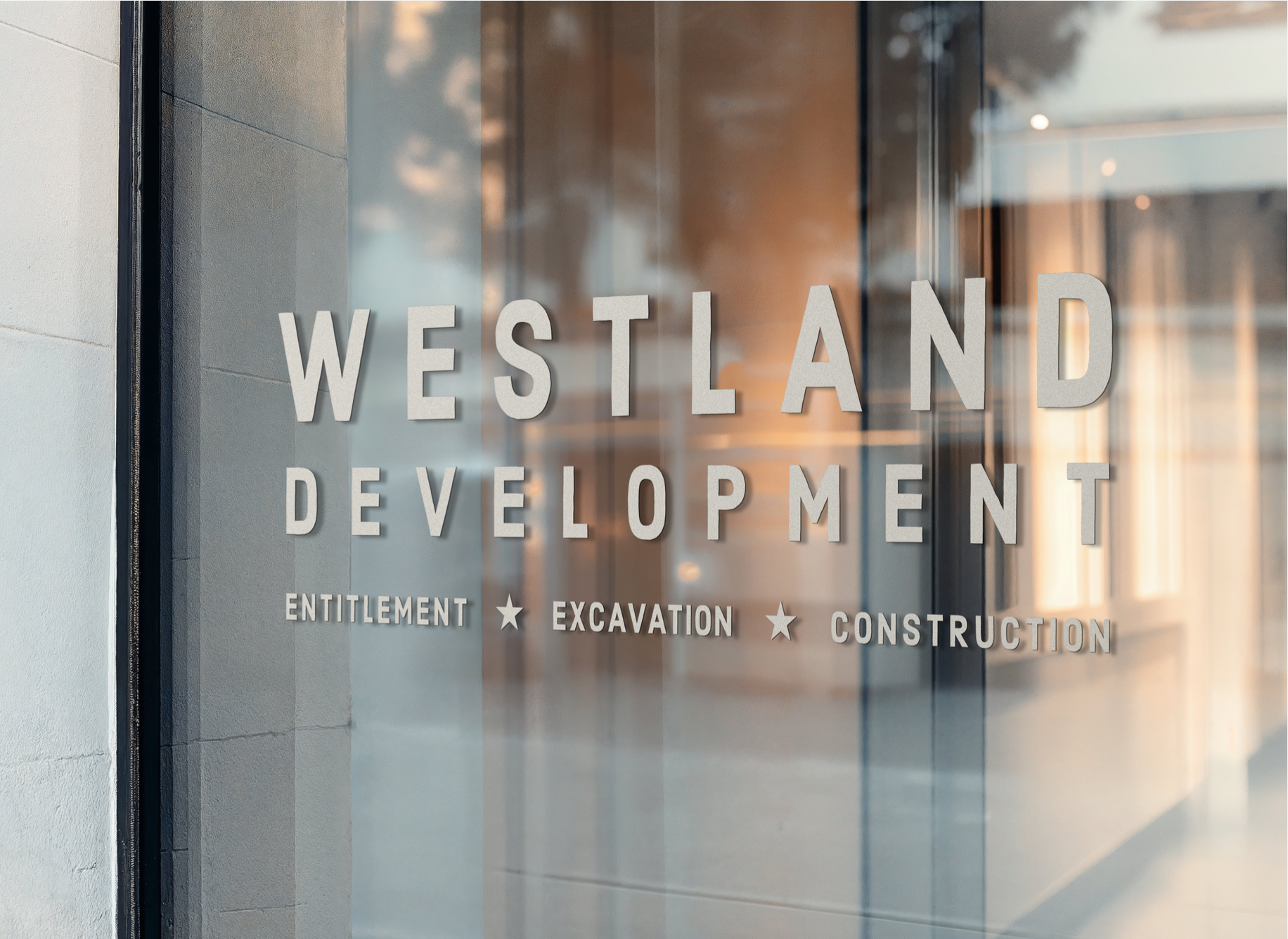 Glass windows with the text 'Westland Development' and words 'Entitlement,' 'Excavation,' and 'Construction' underneath, indicating a development company's office.