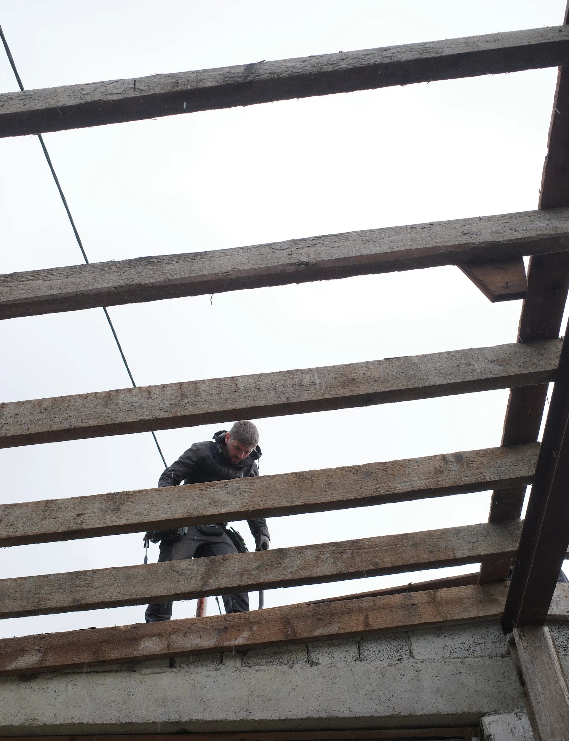Construction worker standing on a wooden plank framework above a concrete structure, looking down.