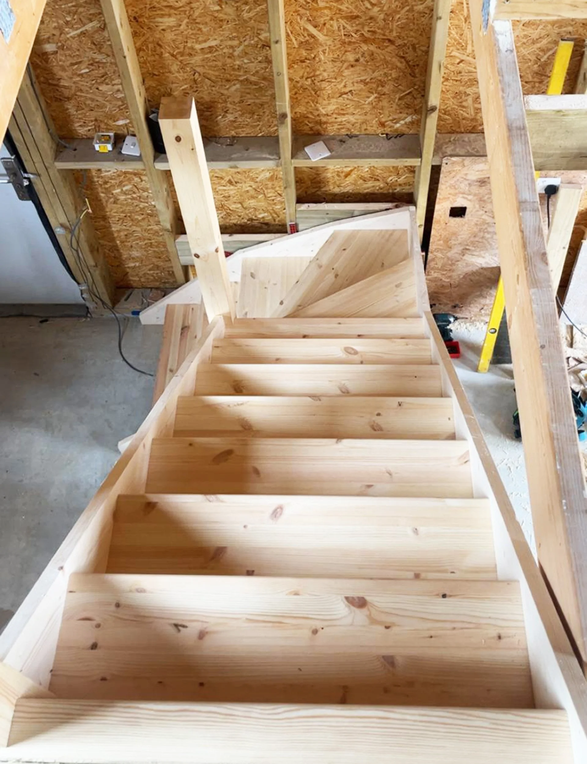 Wooden staircase under construction in a garage or workshop.