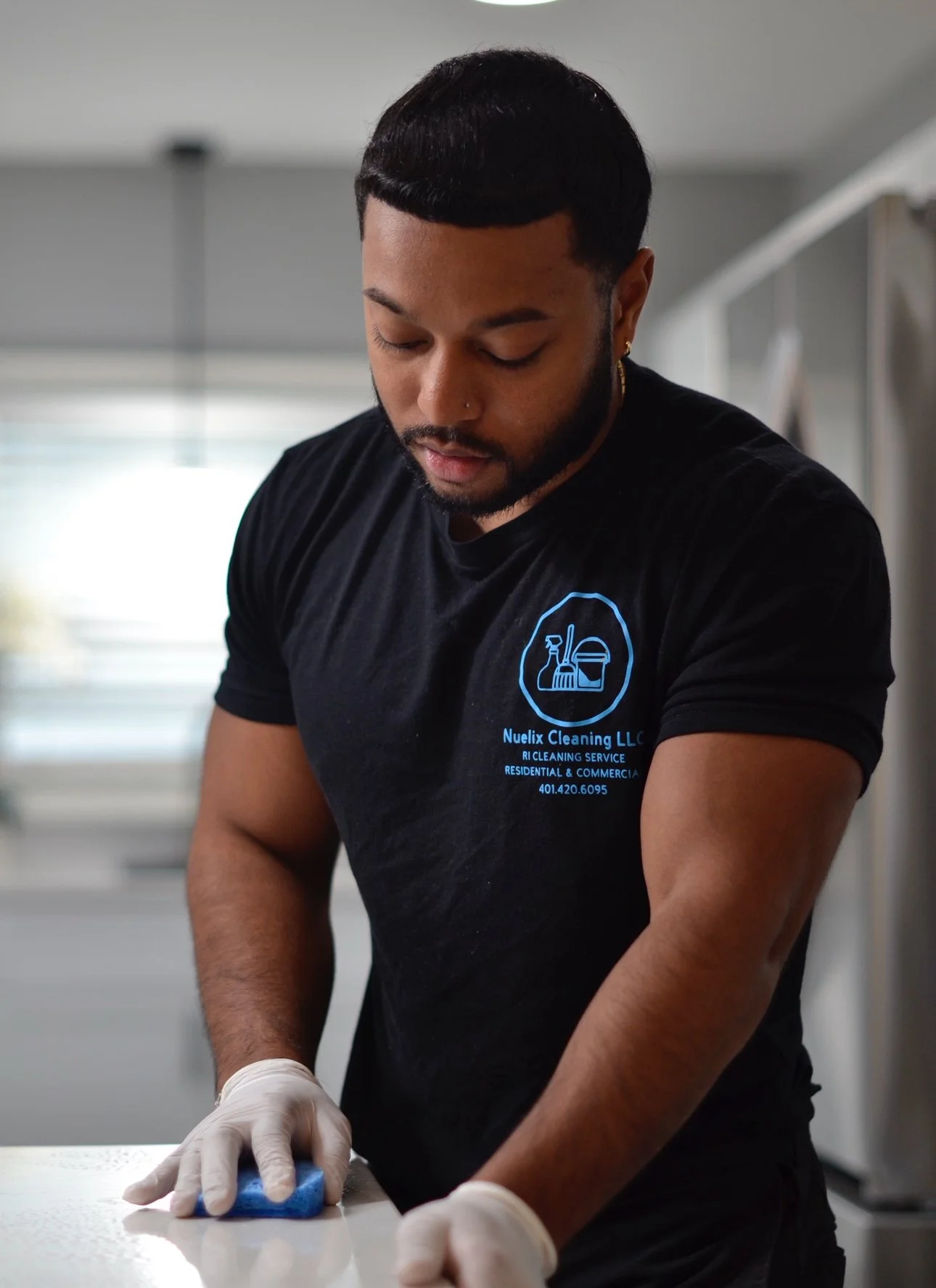 Professional cleaner wearing gloves scrubbing a countertop with a blue sponge