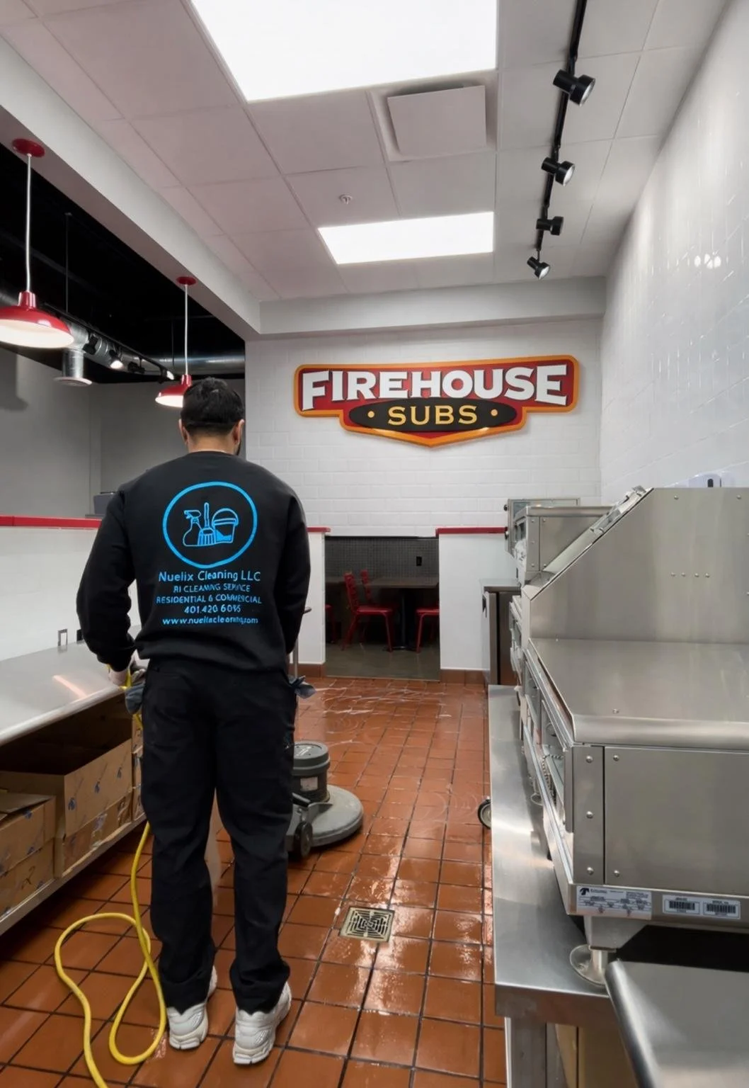 Commercial kitchen cleaner working inside a Firehouse Subs restaurant with industrial equipment and wet tile floors