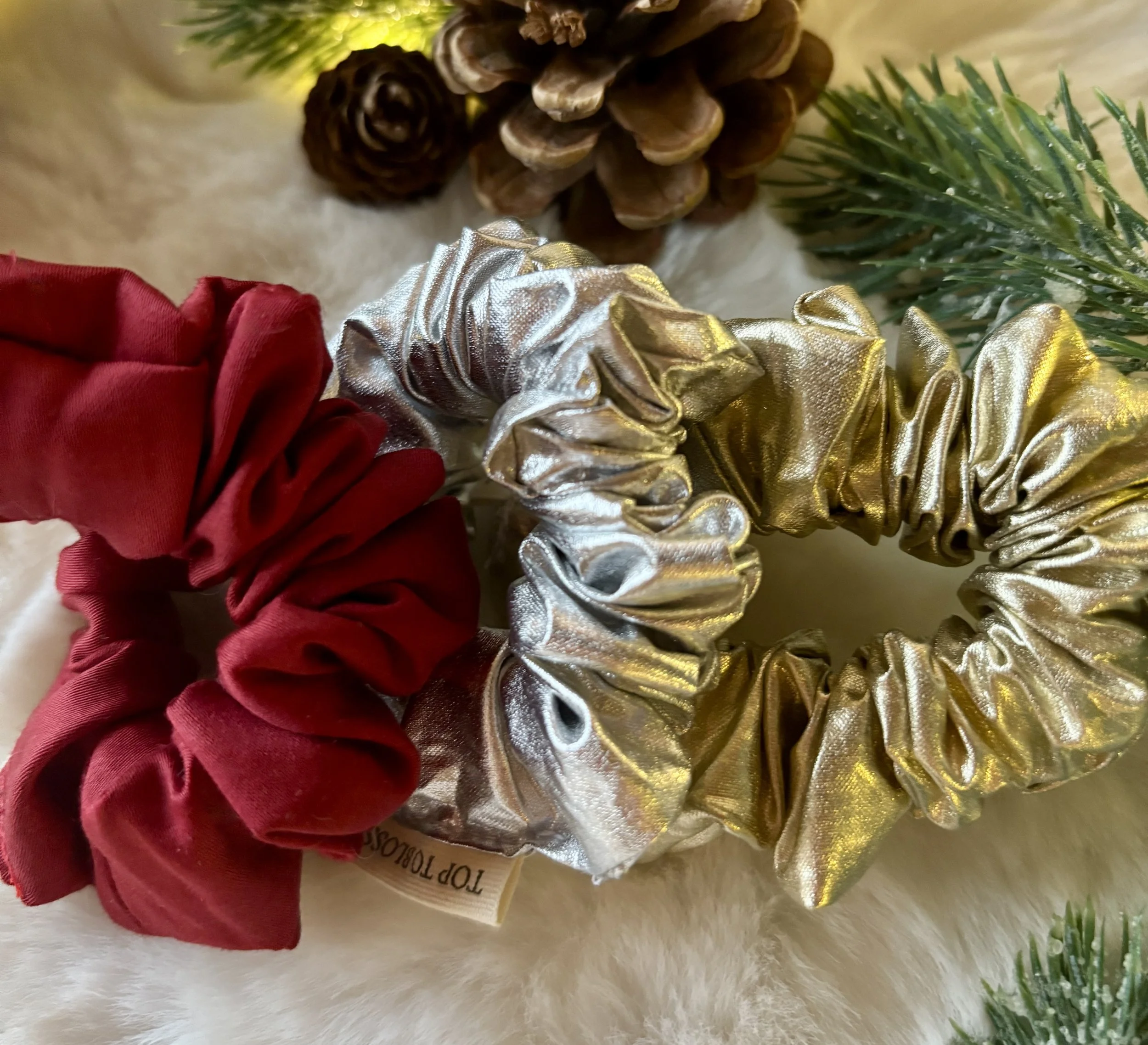 Drie feestelijke haar scrunchies, een in rood katoensatijn, een in zilveren gecoate katoen en een in gouden gecoate katoen. Ideaal voor vrouwen of meisjes met lang haar die er extra feestelijk willen uitzien deze feestdagen.