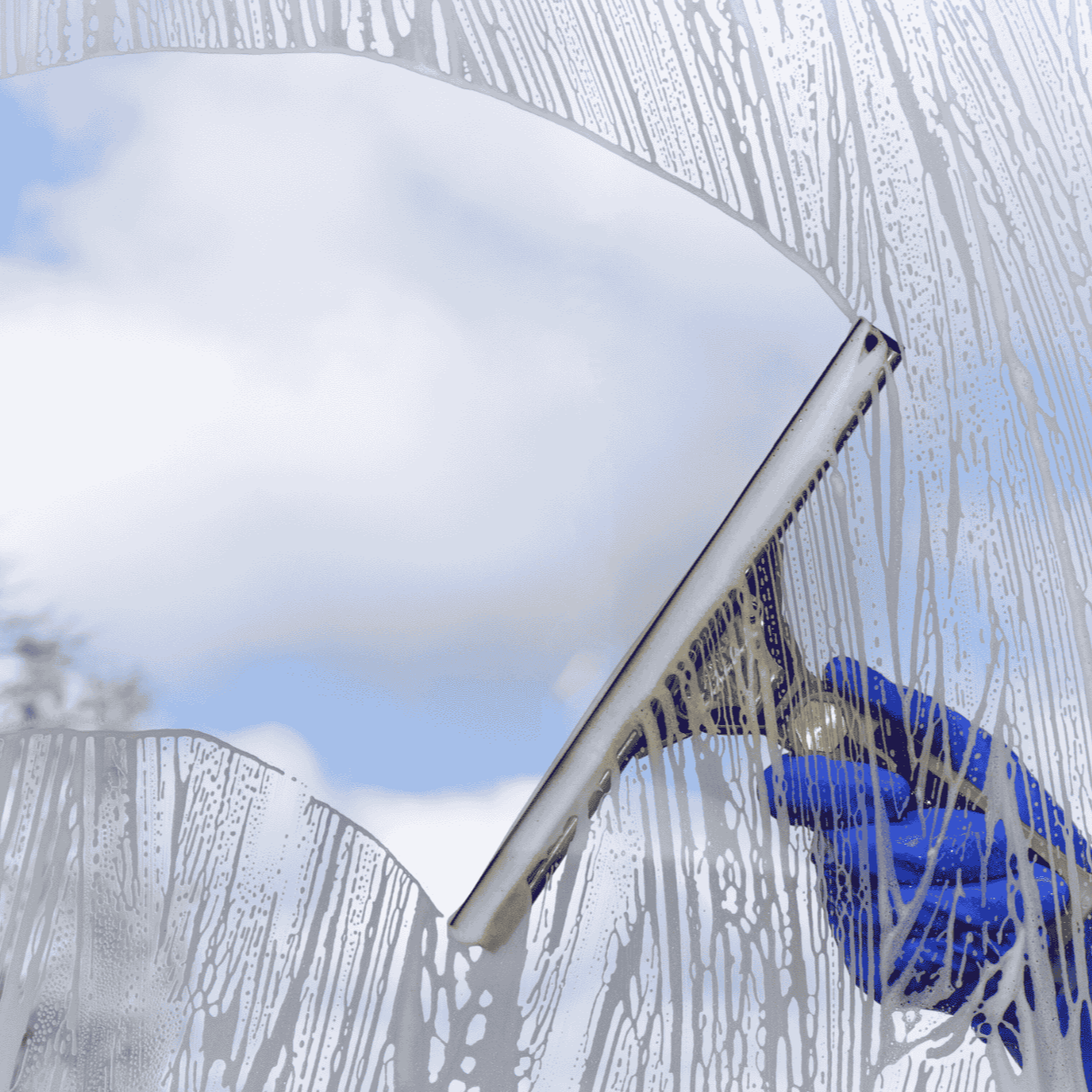 Hand, die einen Fensterwischer an einem verschmutzten Fenster benutzt, während es regnet.