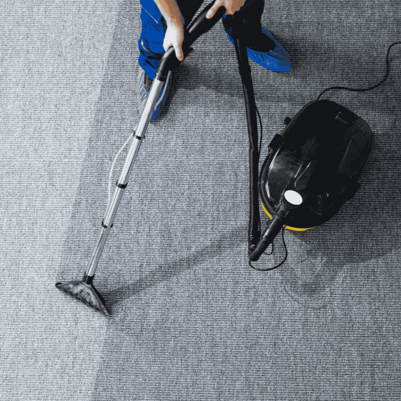 Person reinigt Teppichboden mit Vernebler und Staubsauger.