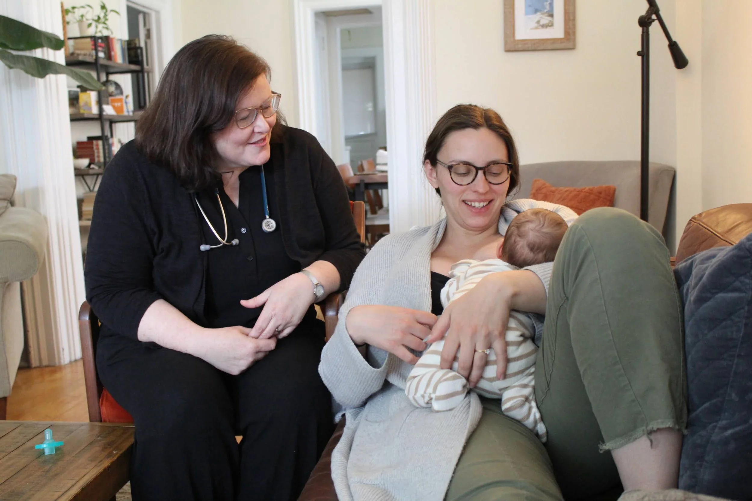 A nurse helps a new mom nurse her newborn baby