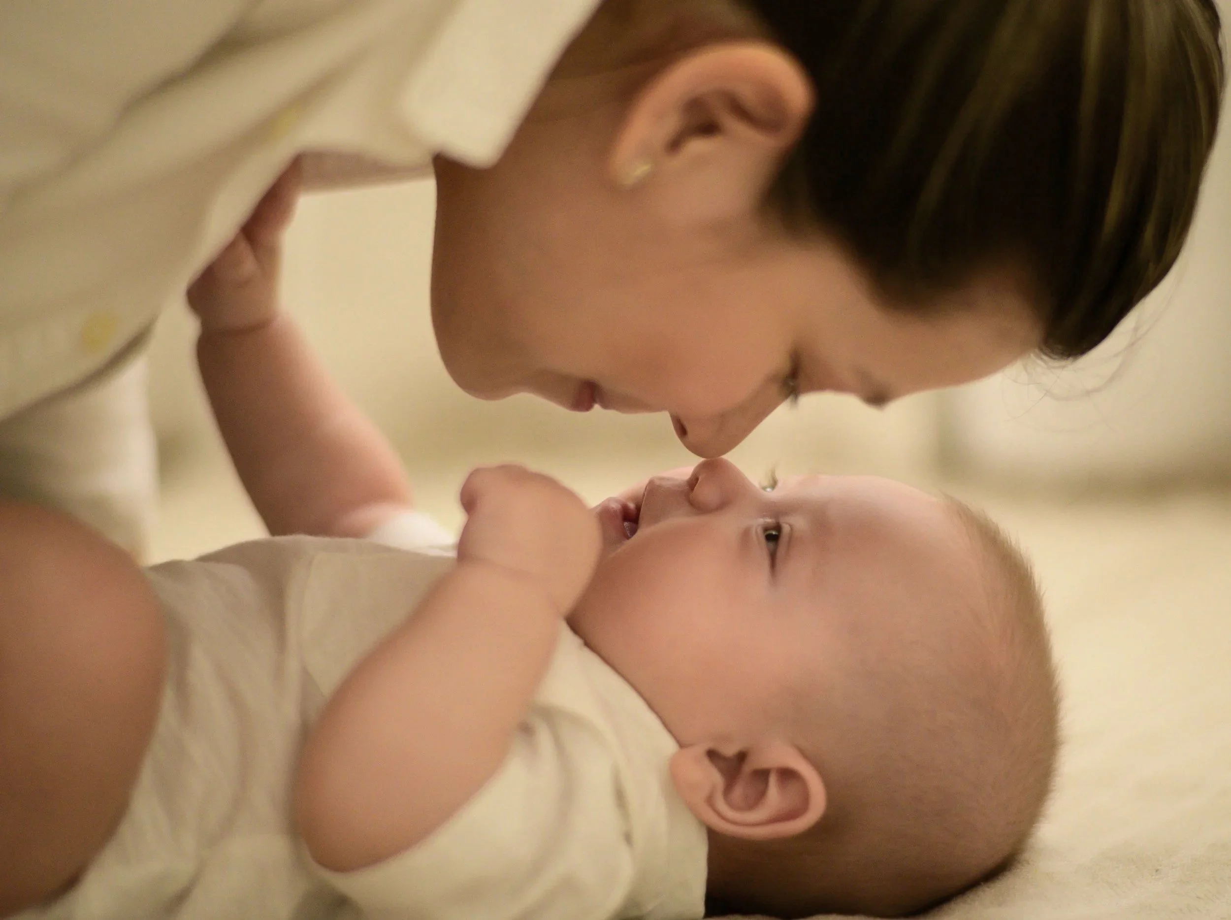 a mother leans down to kiss a newborn baby