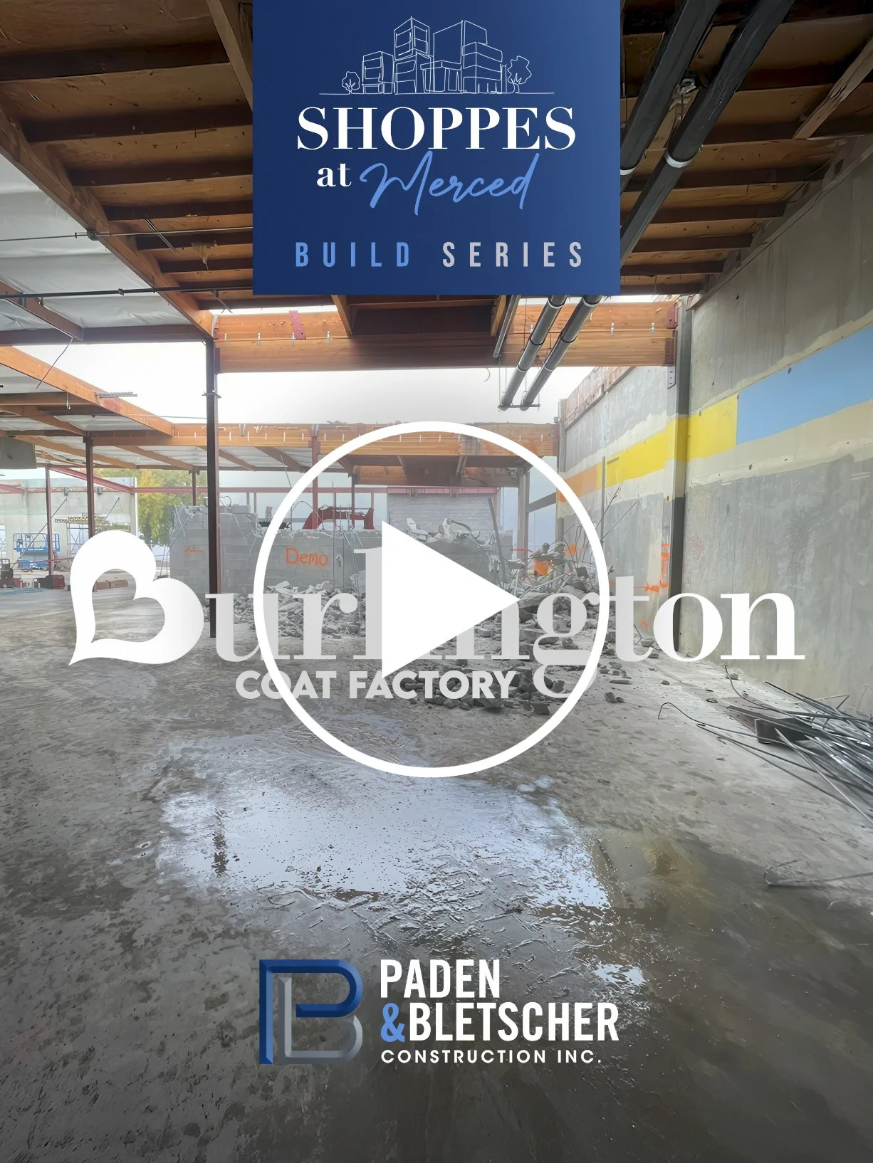 Construction site with wet concrete floor, partially built structure with wooden beams and metal supports, and signs for 'Shoppes at Merced Build Series' and 'Burlington Coat Factory'.