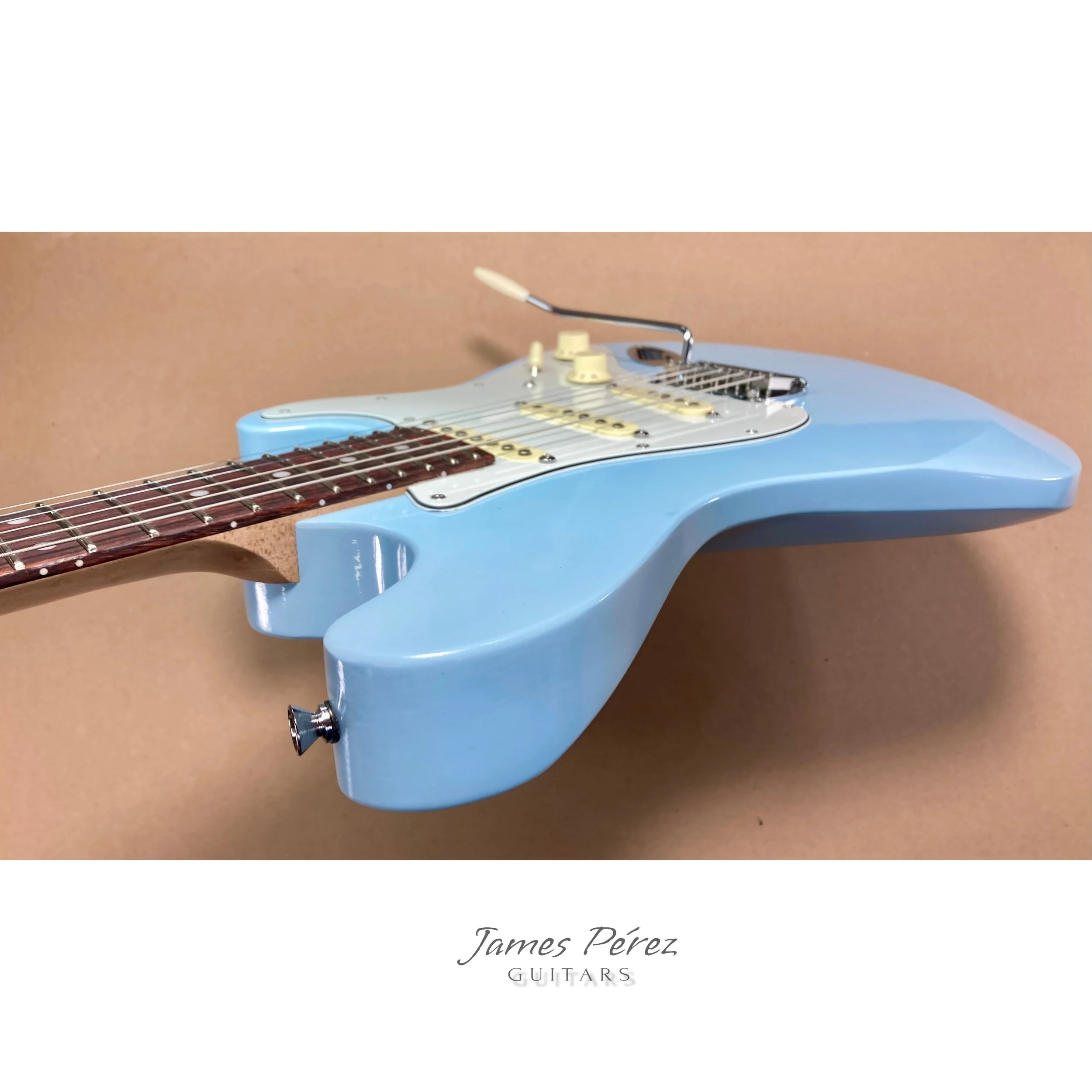 Light blue electric guitar with a wooden neck and various control knobs, set against a plain background.