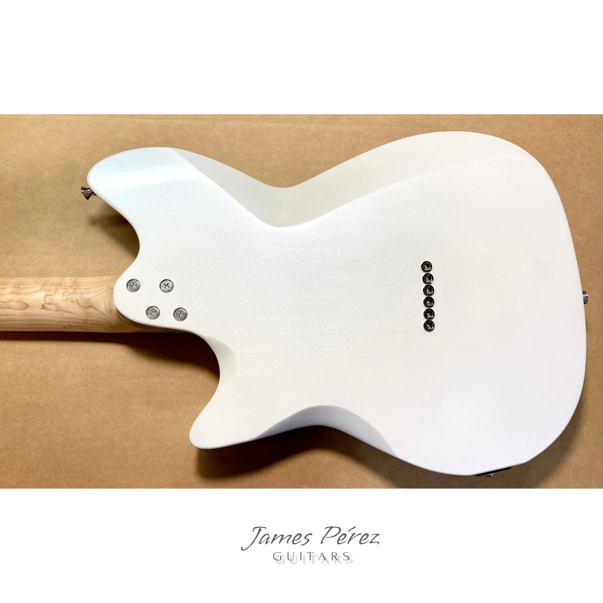 A white electric guitar with a natural wood neck, shown from the back, with the logo 'James Pérez Guitars' underneath.